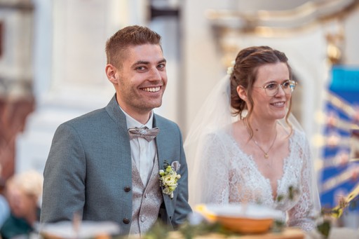 Brautpaar küsst sich nach der Trauung vor Gästen bei Hochzeit im Freien vor Kapelle