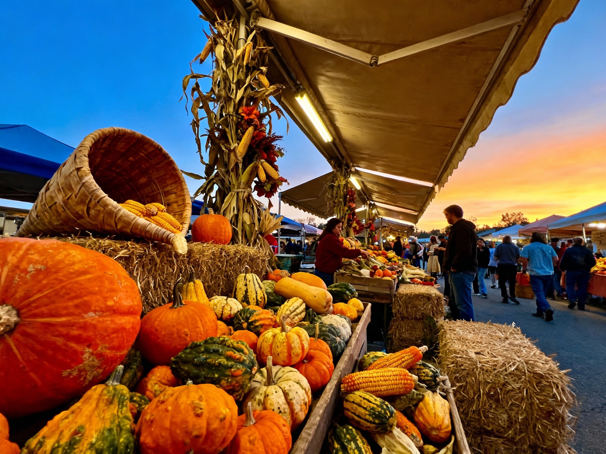 A view of a vibrant Thanksgiving harvest festival scene at dusk, with dynamic