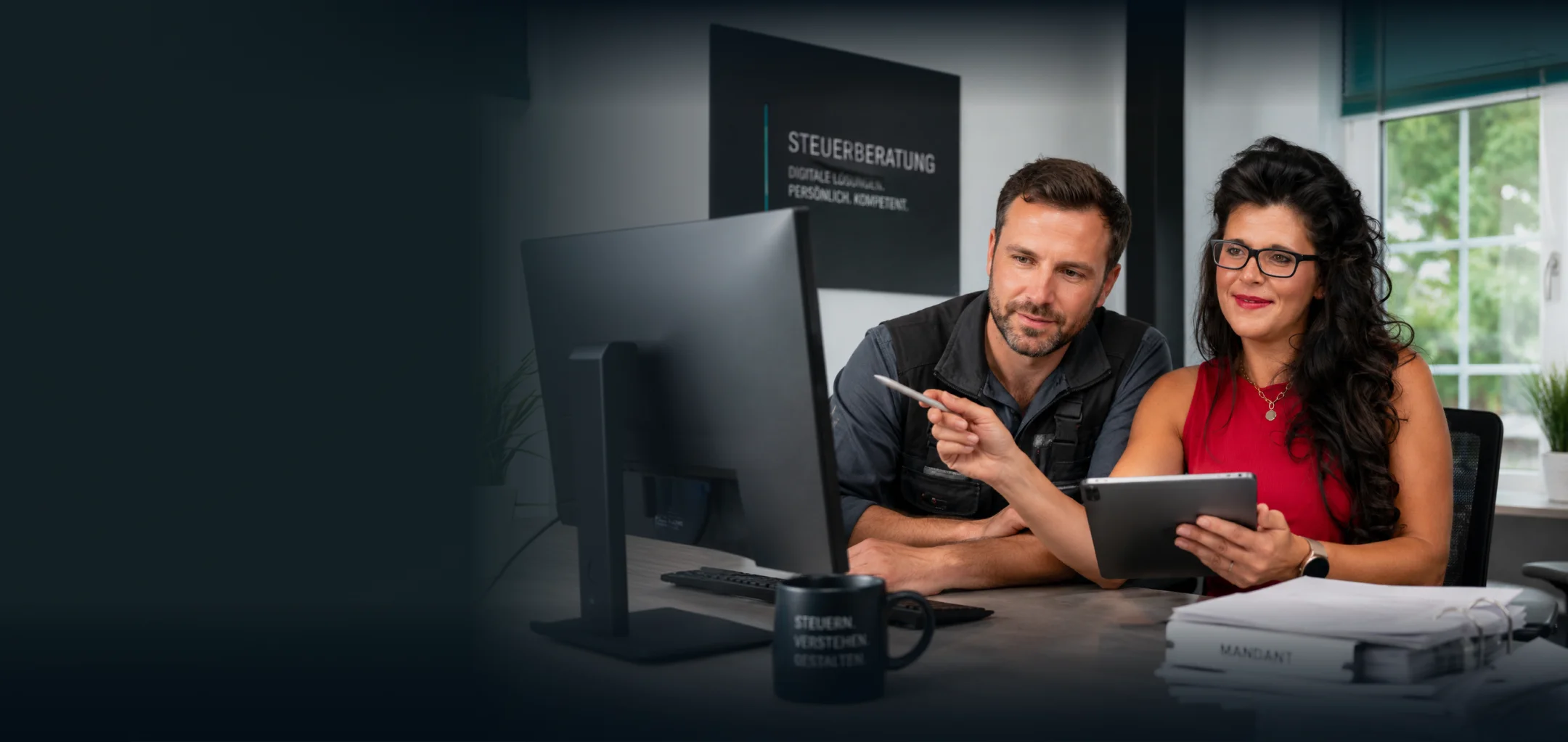 Steuerberater und Steuerberaterin der GKK besprechen an einem Bildschirm die Zahlen eines Handwerksbetriebs