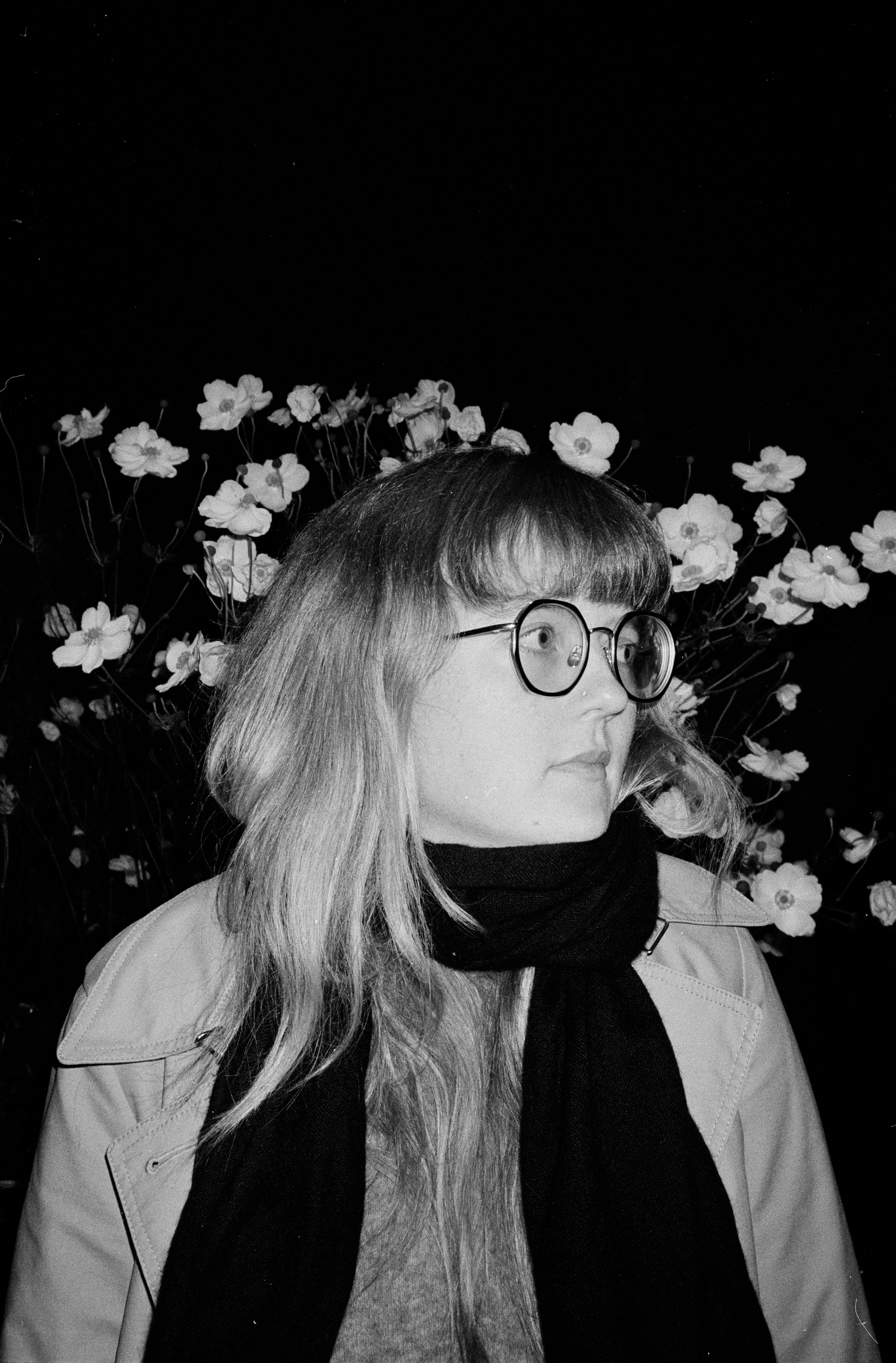 Woman wearing glasses and scarf with flowers behind