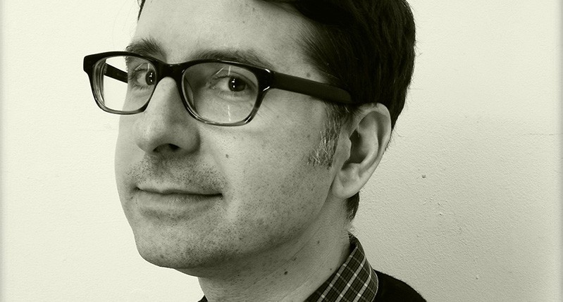 A black and white photo of a man wearing glasses and a shirt.