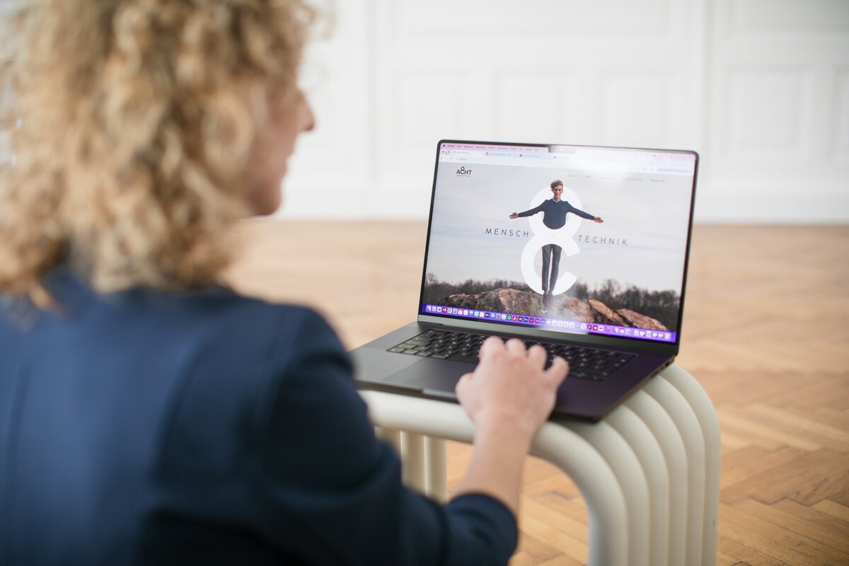 UI/UX-Designerin arbeitet am Laptop an einer Website mit Fokus auf Mensch und Technik
