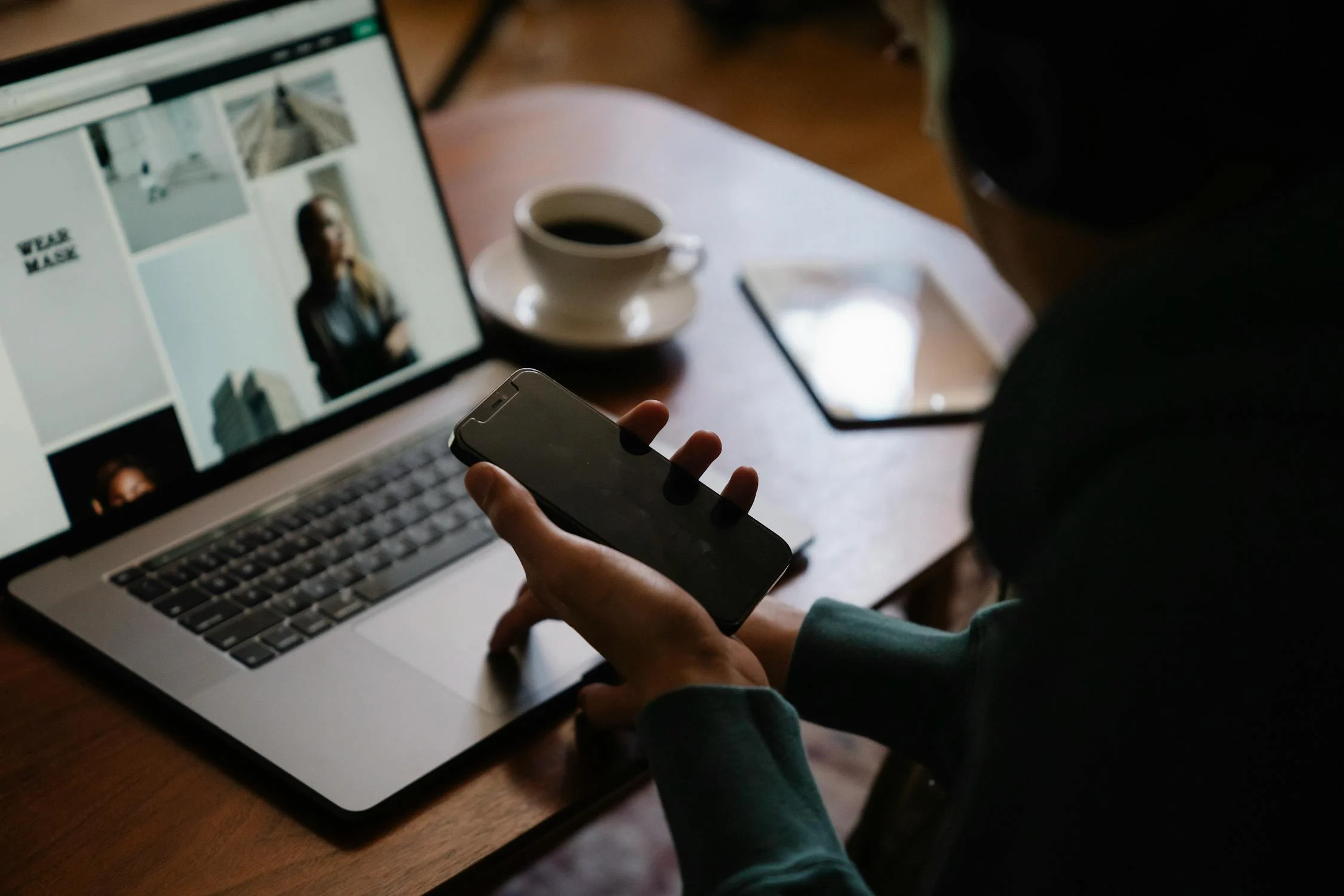 a person holding a phone and looking at a laptop screen - portray digital