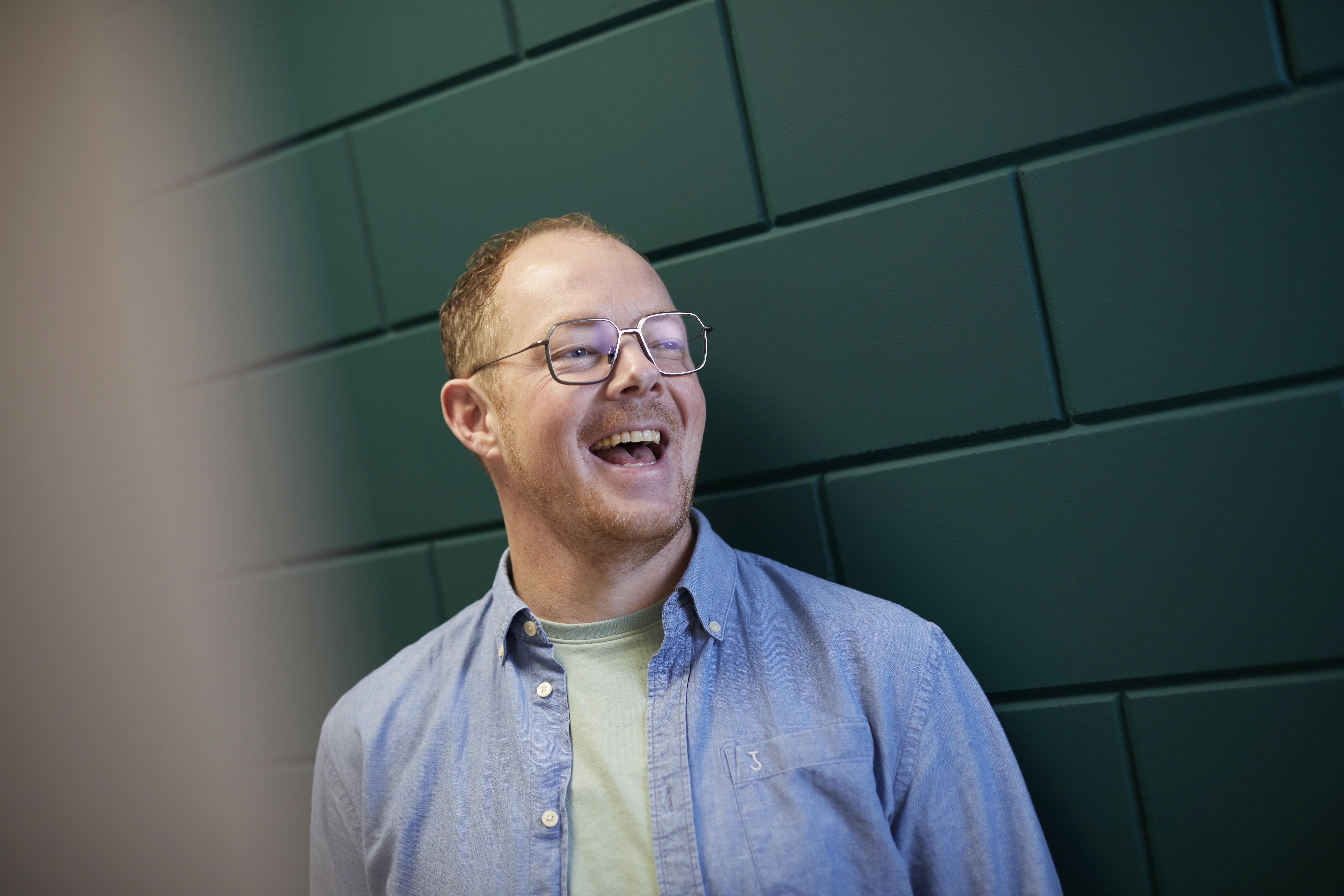 Een kind zit op een bank en aait zachtjes een zwarte hond in een met zonlicht gevulde kamer.