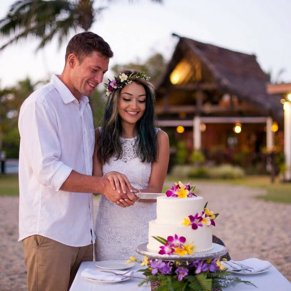 A couple cutting their wedding cake at Uprising Beach Resort Fiji at dusk