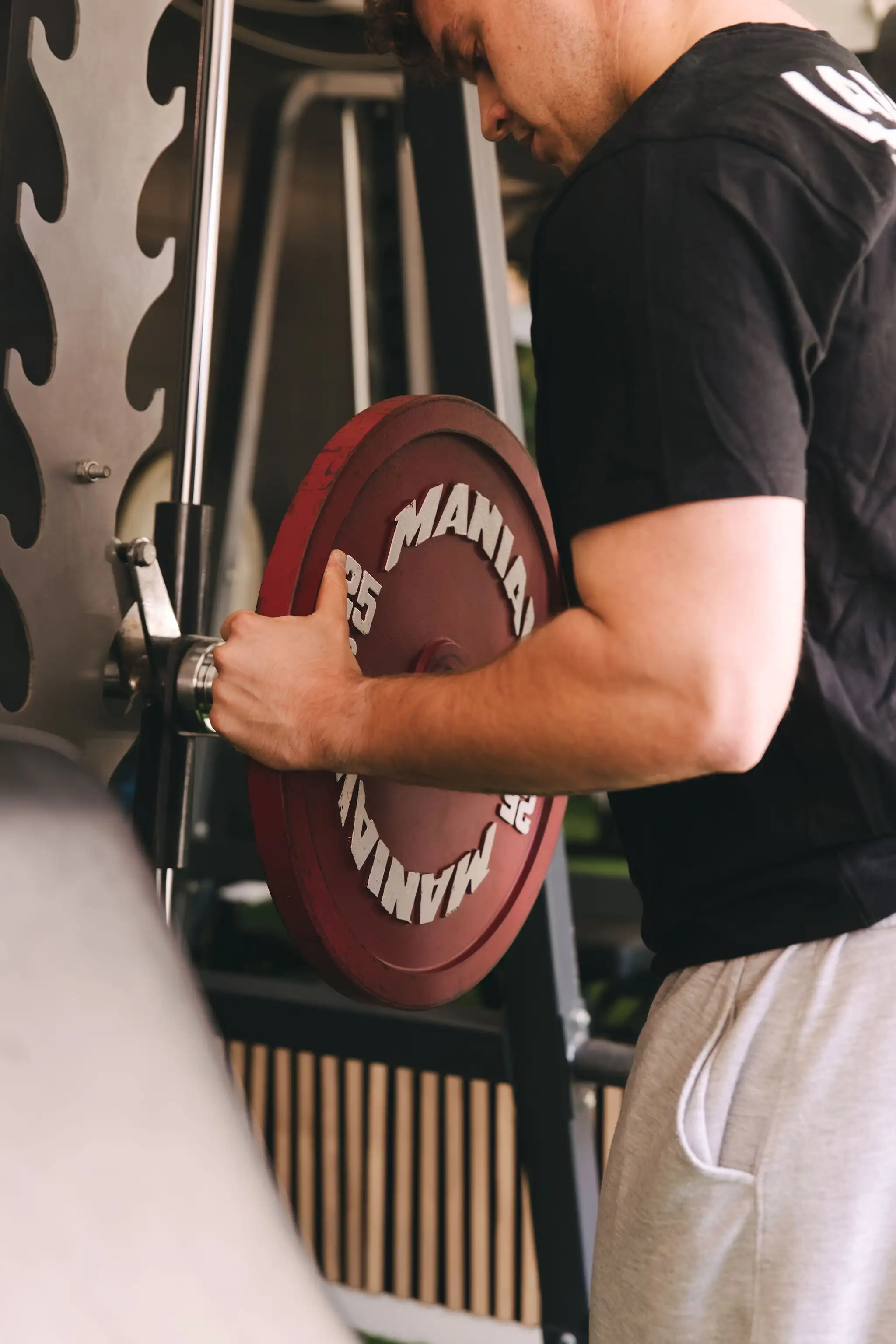 Entrenador colocando las pesas a máquina en La Base Strength, Vilanova i la Geltrú