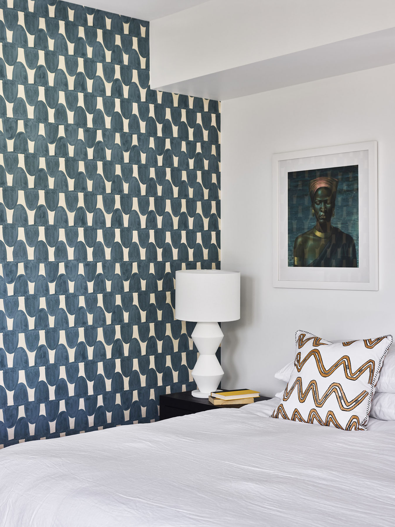 Bedroom with patterned feature wall, bedside lamp, and framed artwork.
