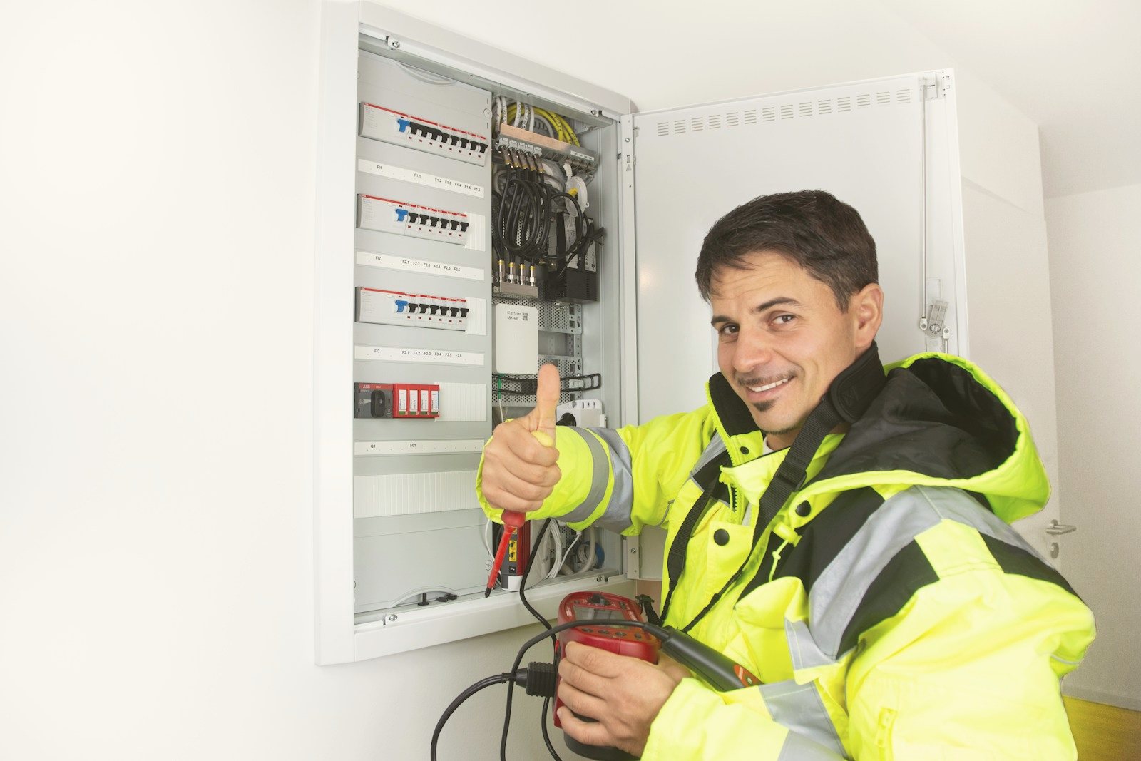 Electrician smiling beside a finished panel