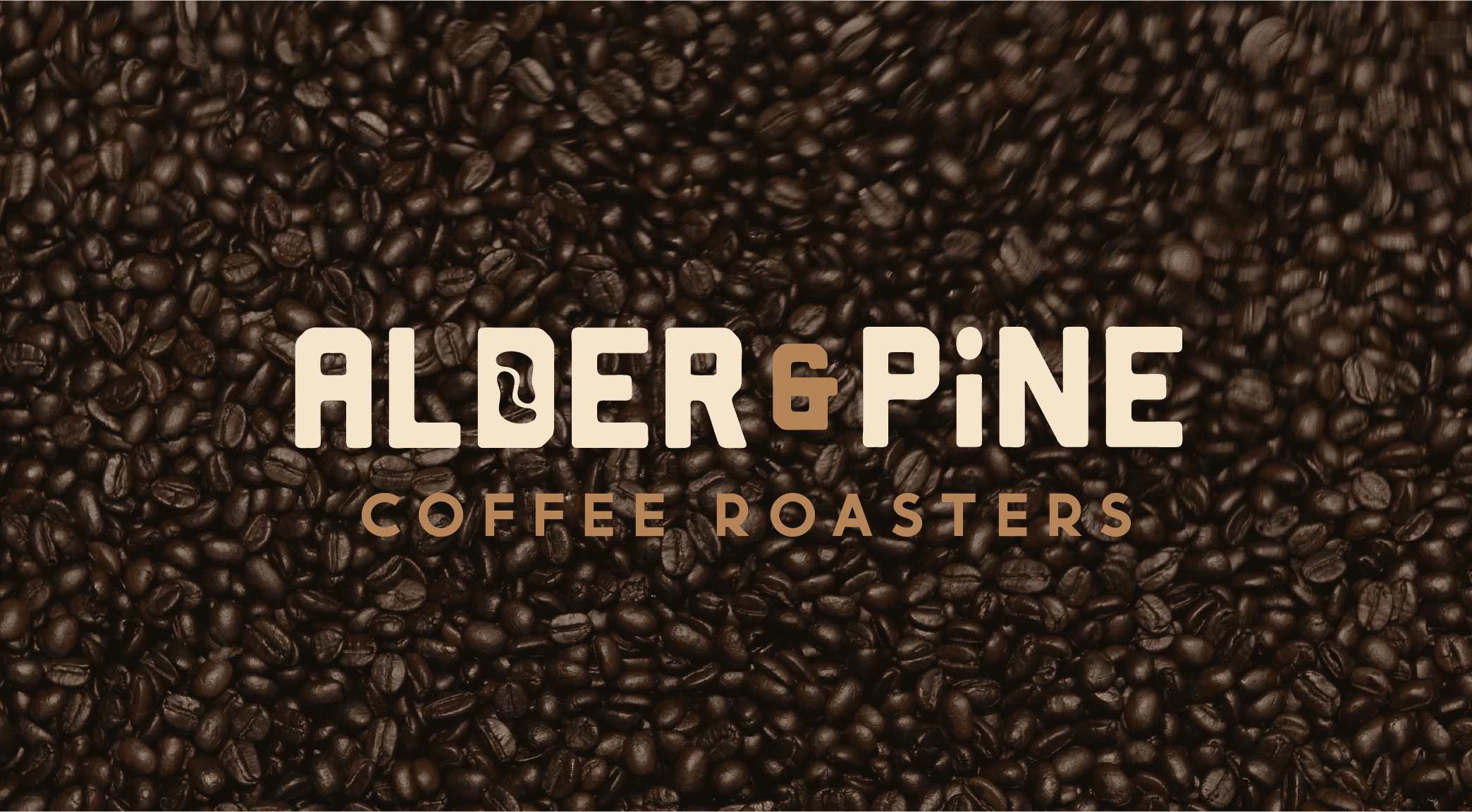 Graphic design mockup of a wordmark for Alder & Pine Coffee Roasters — modern, clean wordmark logo of a footprint and a coffee bean with a bold decorative sans serif typography over a photo of coffee beans, designed by Will Lefkovich.