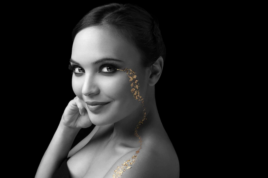 Portrait de mode artistique en noir et blanc avec effets de feuilles d'or et particules dorées sur le visage d'une femme. Photographie de beauté haut de gamme et retouche créative réalisée à l'Île de la Réunion (974) par le photographe David Dijoux. Expertise en post-production visuelle et direction artistique pour projets publicitaires et éditoriaux.