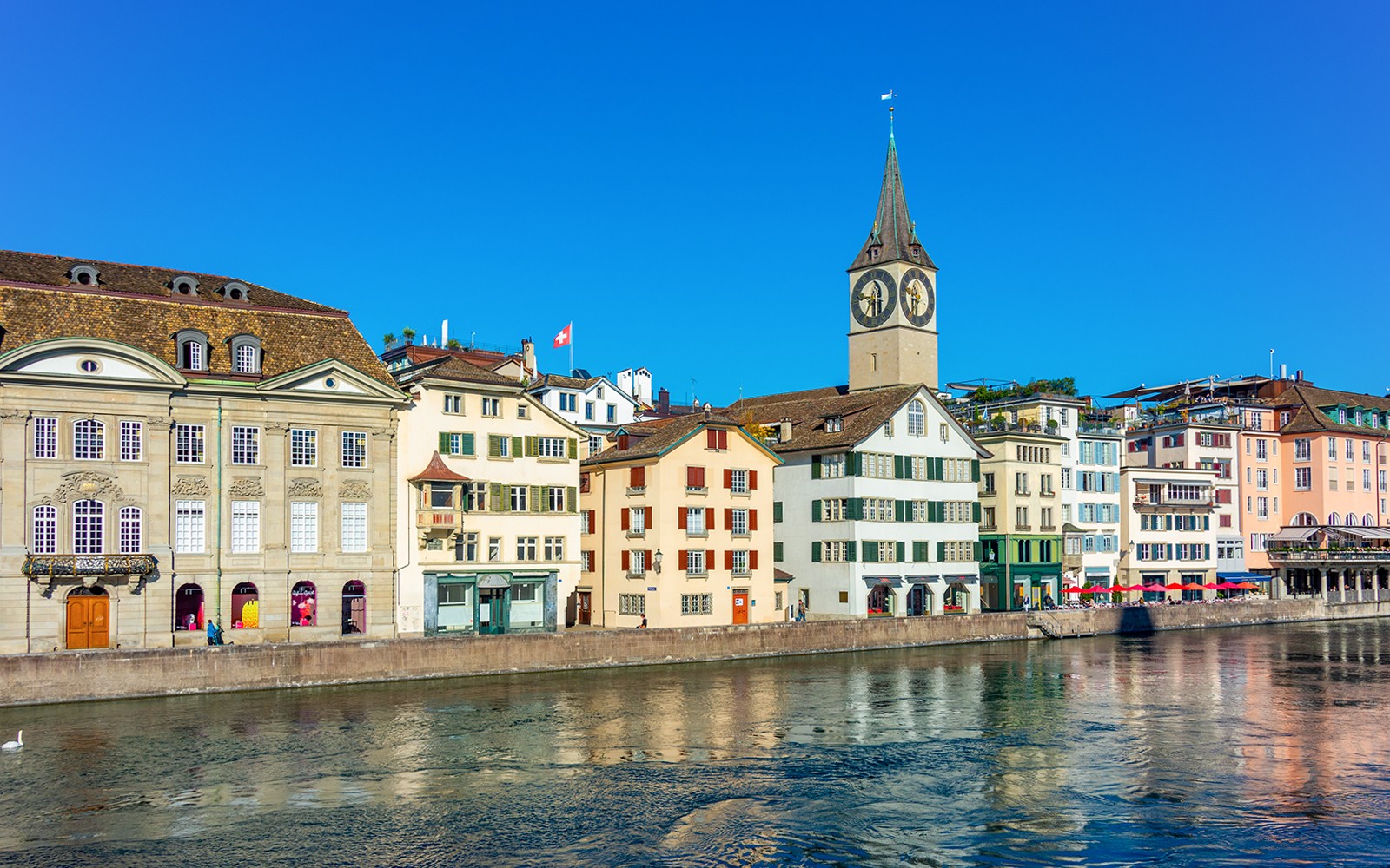 Historiska byggnader längs Limmatfloden med S:t Peterskyrkan i Zürich.