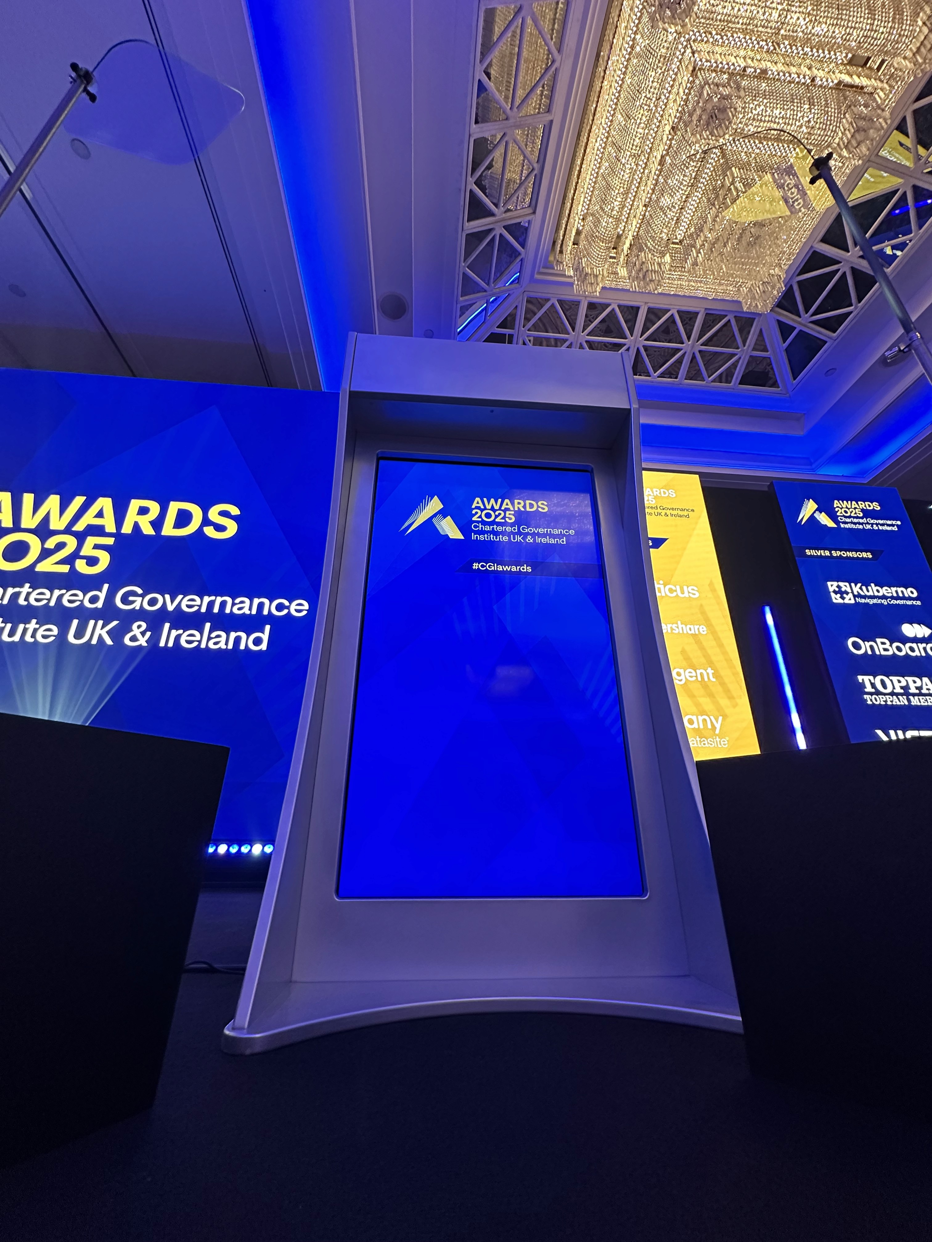 Branded digital lectern on the CGI Awards stage with LED screens visible behind it.