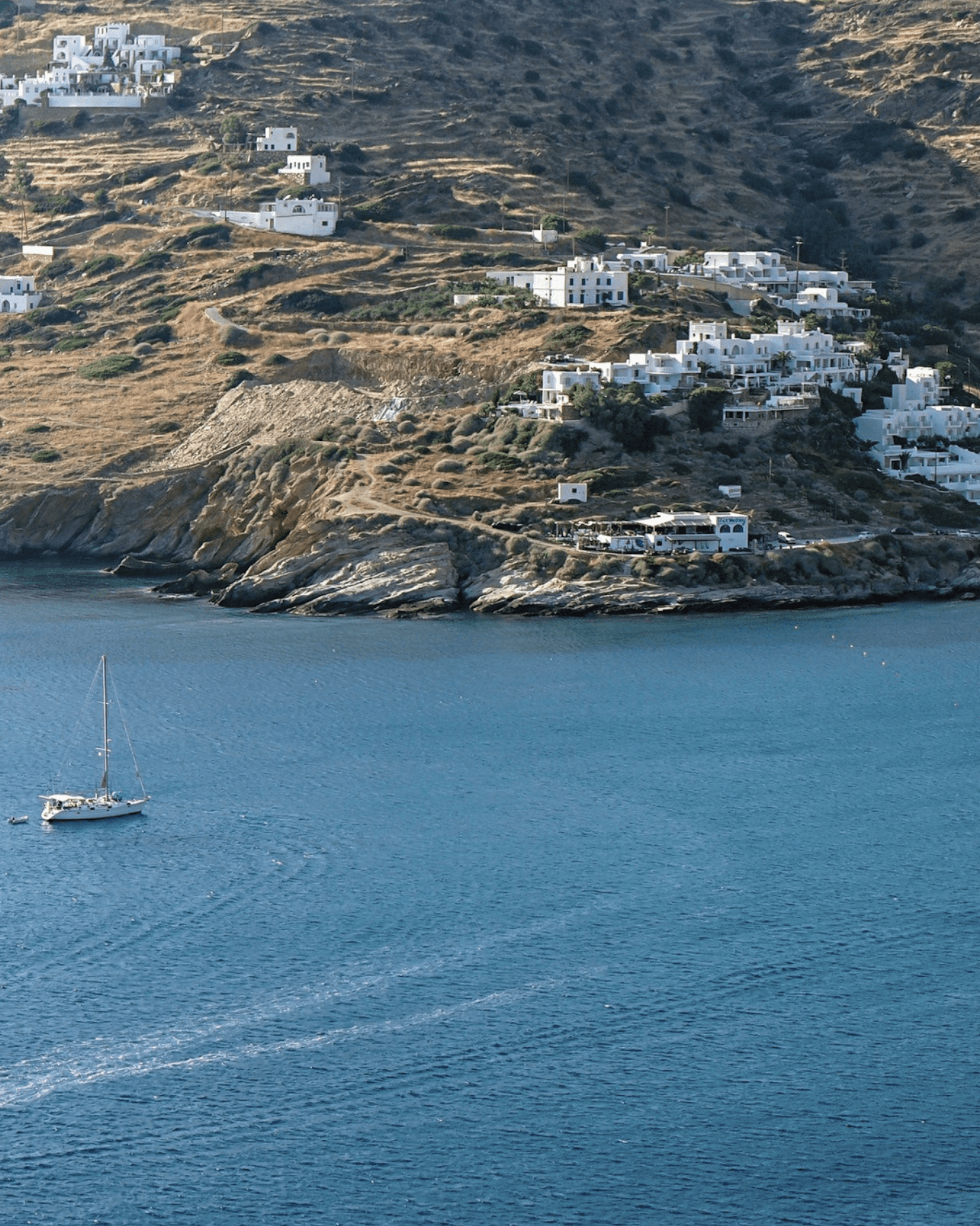 The endless blue view, a catamaran and the village on the mountain top of Ios island.