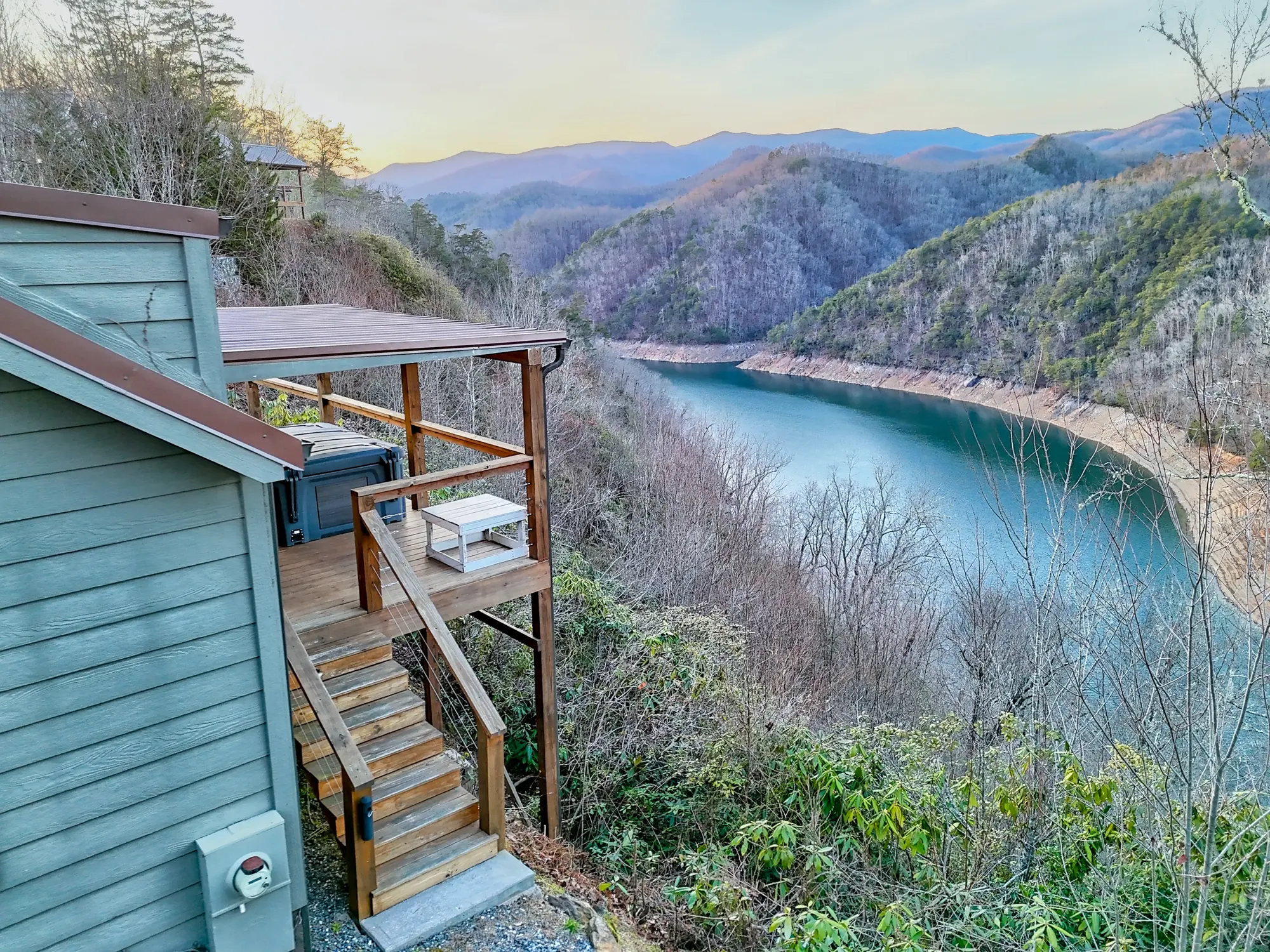 Tiny Tuck deck and stairs on the ridge edge, with Fontana Lake curving below at sunset