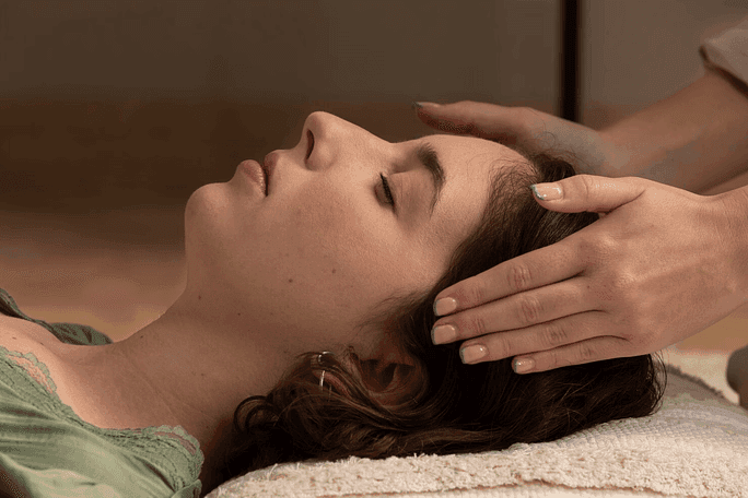 Close-up of a woman enjoying a calming head massage at a wellness spa