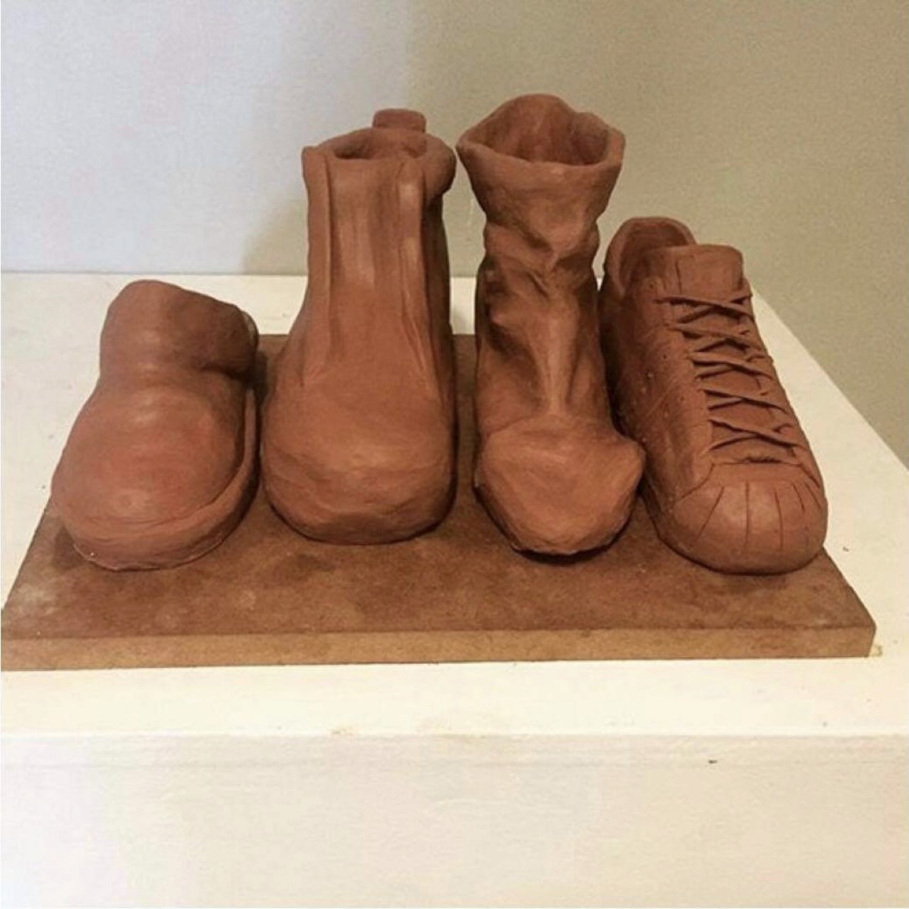 Image of four clay shoe sculptures crafted by hand, each depicting a different foot defect related to the human body.