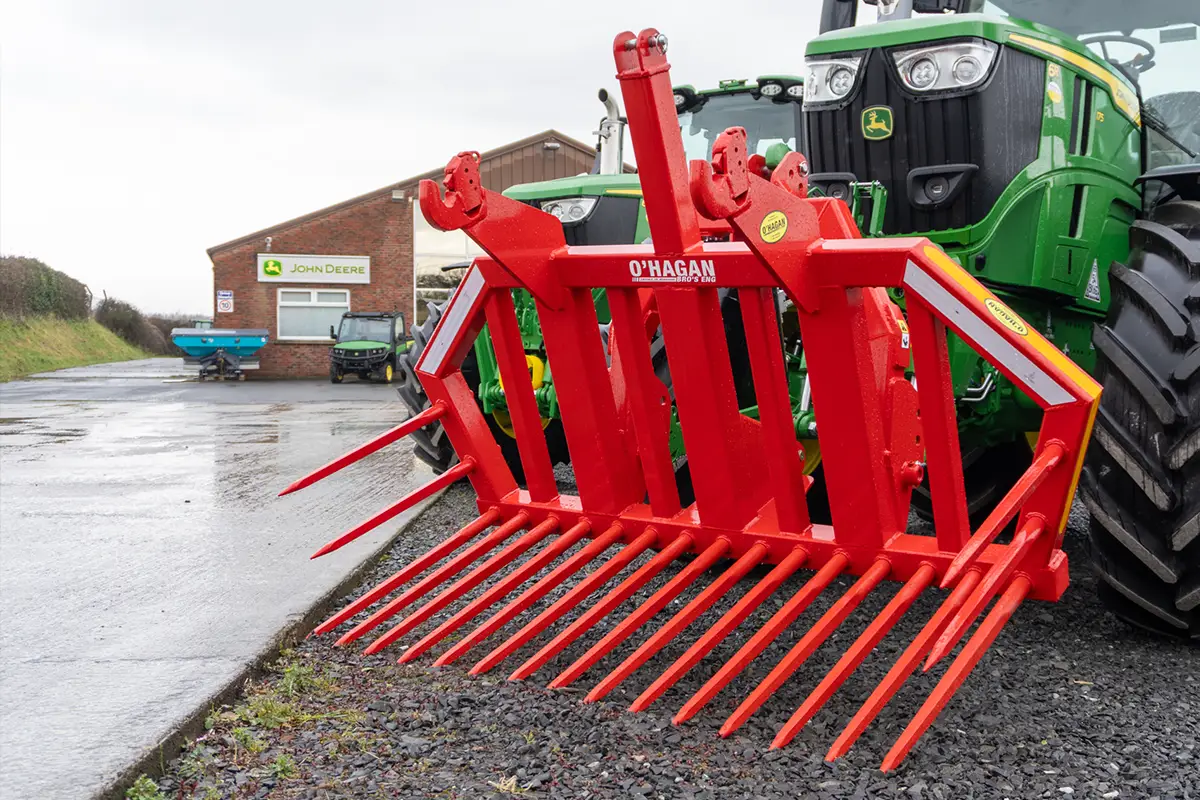 Red stone fork attached to a Green John Deere tractor in the carpark of a John deere office