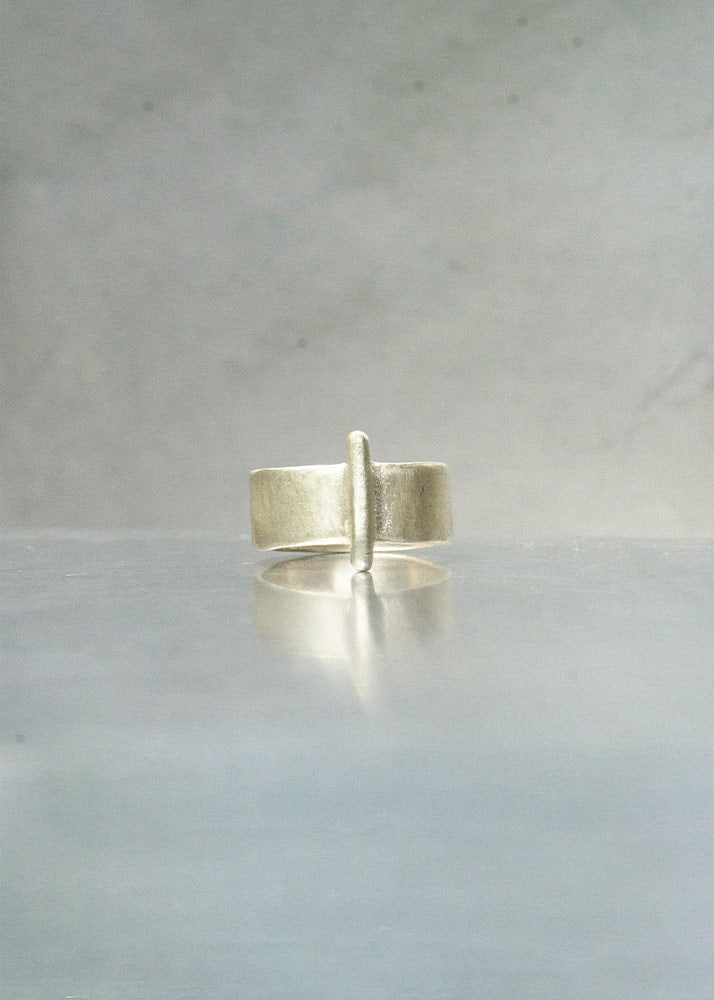 Silver ring on a reflective surface with a neutral background