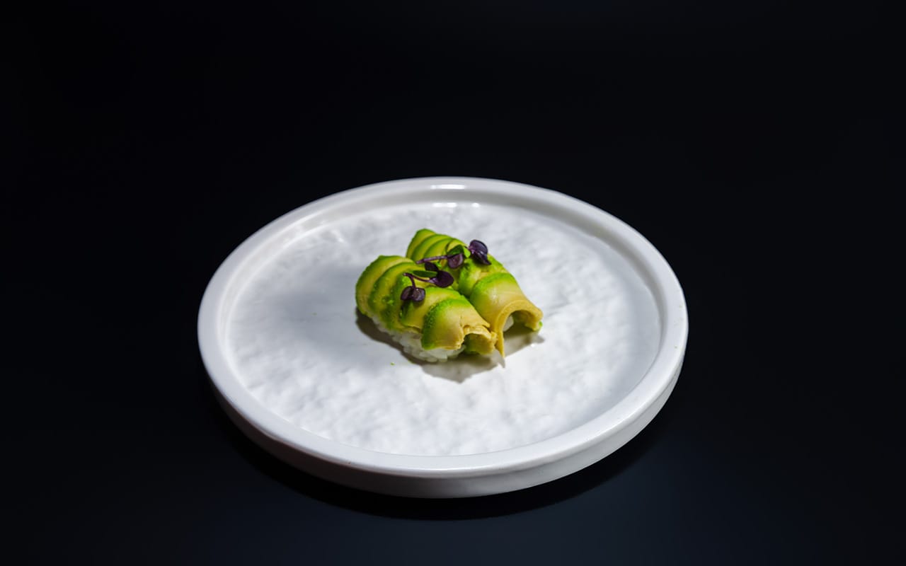 sushi on black ceramic plate beside sauce bottle