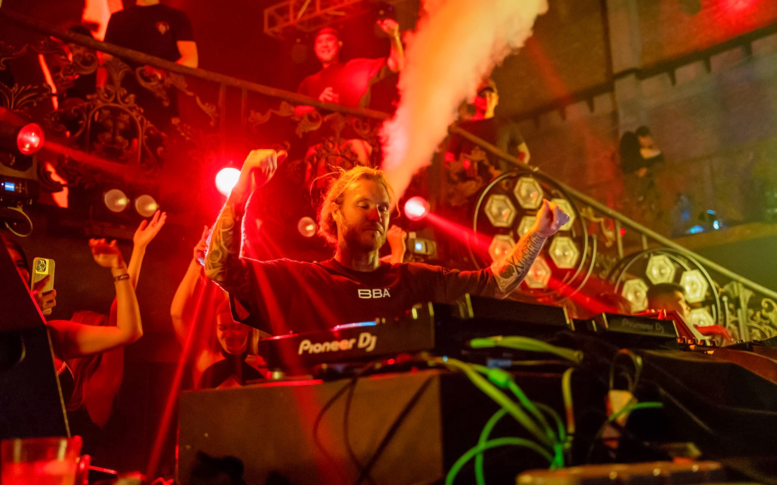 DJ tampil di Atlas Super Night Club, Bali, dengan lampu berwarna-warni dan kerumunan yang energik.