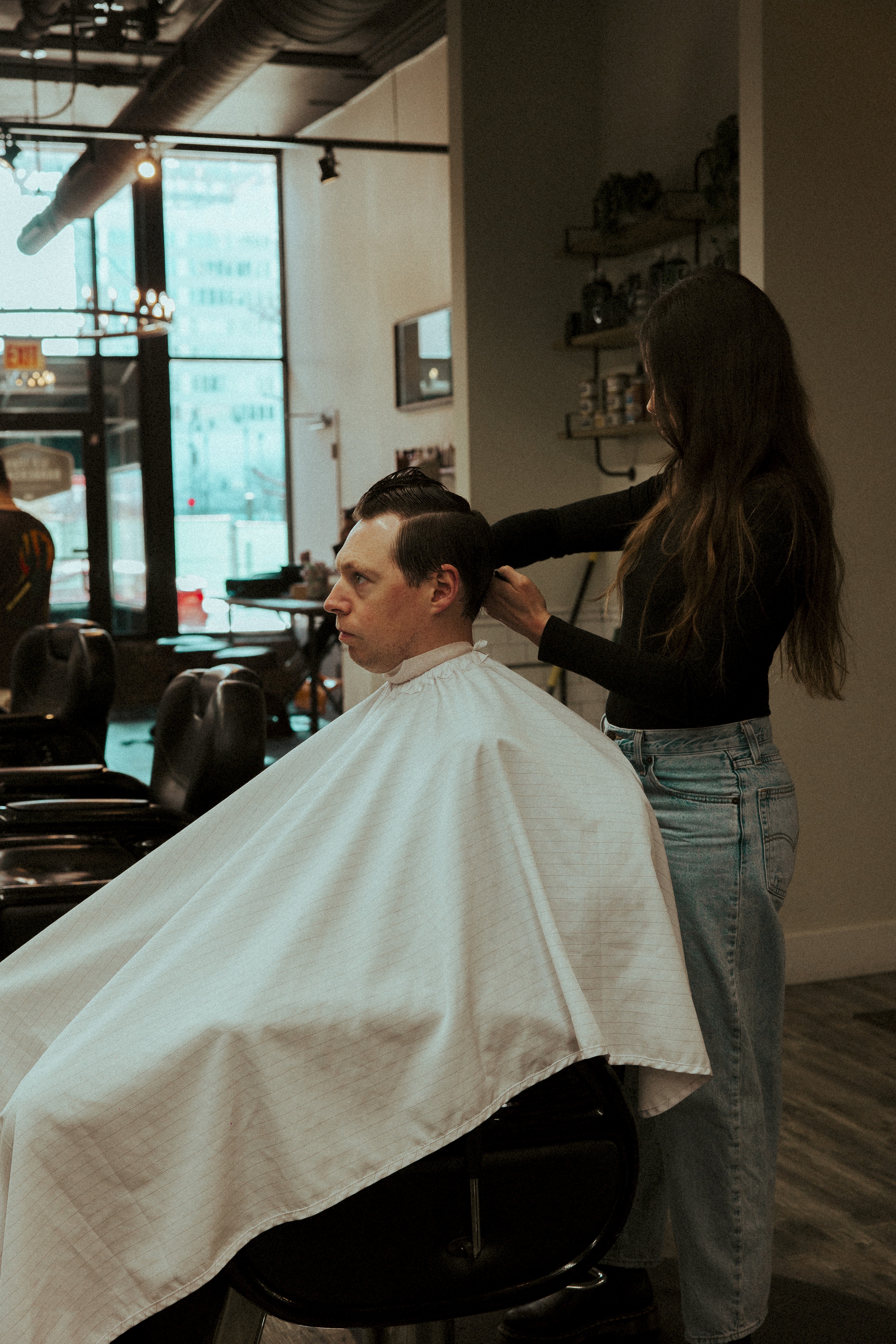A barber styling a client’s hair at Old Town Barber in Chicago, showcasing the shop’s warm atmosphere and professional haircut experience.