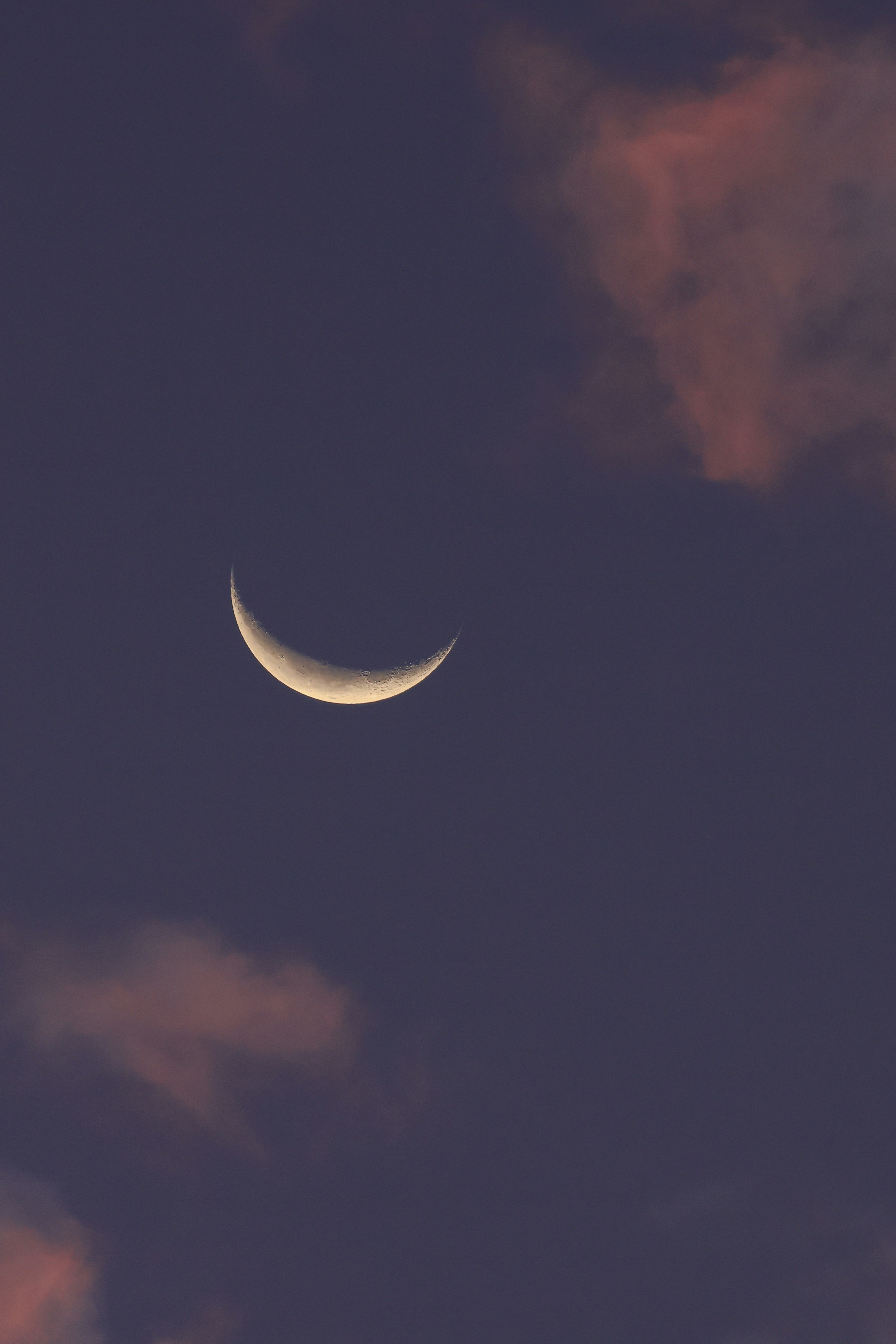 Crescent moon in a dusky sky with clouds