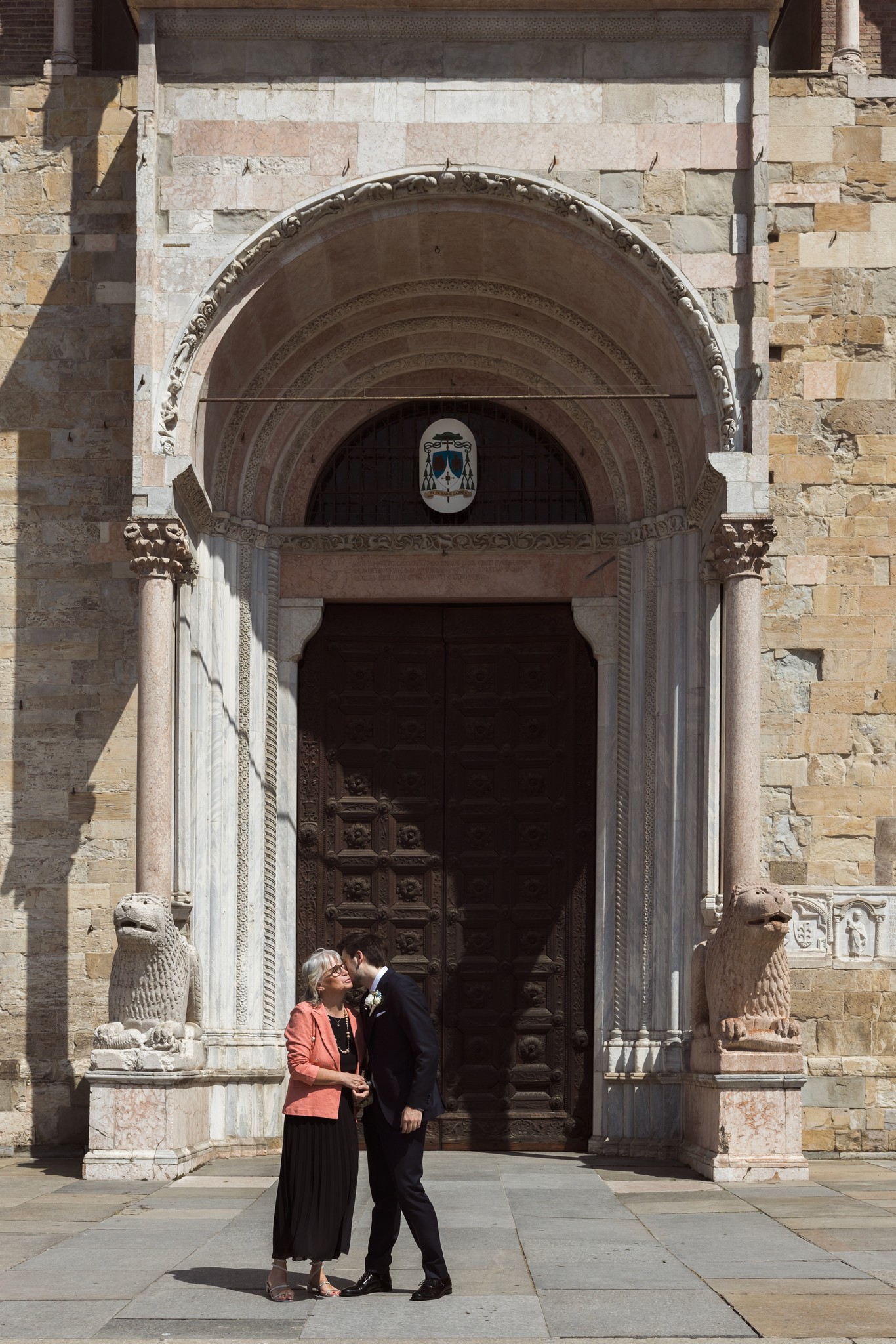 Francesca e Matteo varcan il portale di Villa Peroni Riva, luce dorata sui sampietrini, cerimonia matrimoniale in Toscana