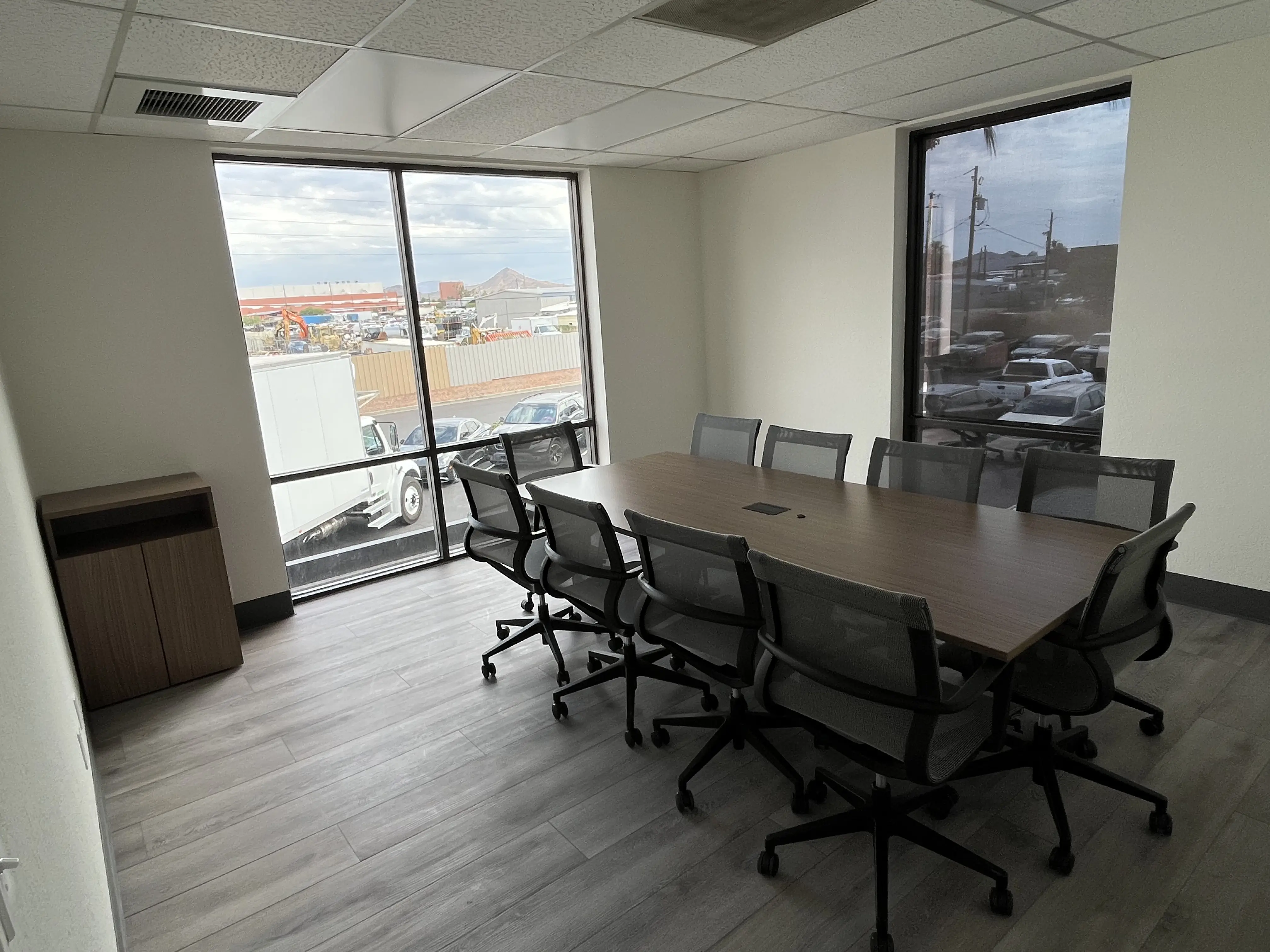 Modern conference room with a large wooden table and eight ergonomic mesh chairs.