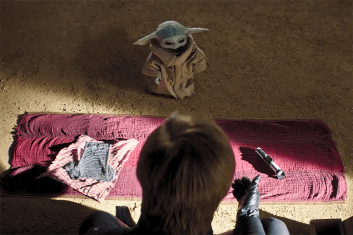 Grogu stands before Luke Skywalker, faced with a life-changing decision. In front of him lie two objects: Yoda’s lightsaber, representing the Jedi path, and a small Beskar chainmail shirt, symbolizing his bond with Din Djarin. The weight of his choice lingers in the air.