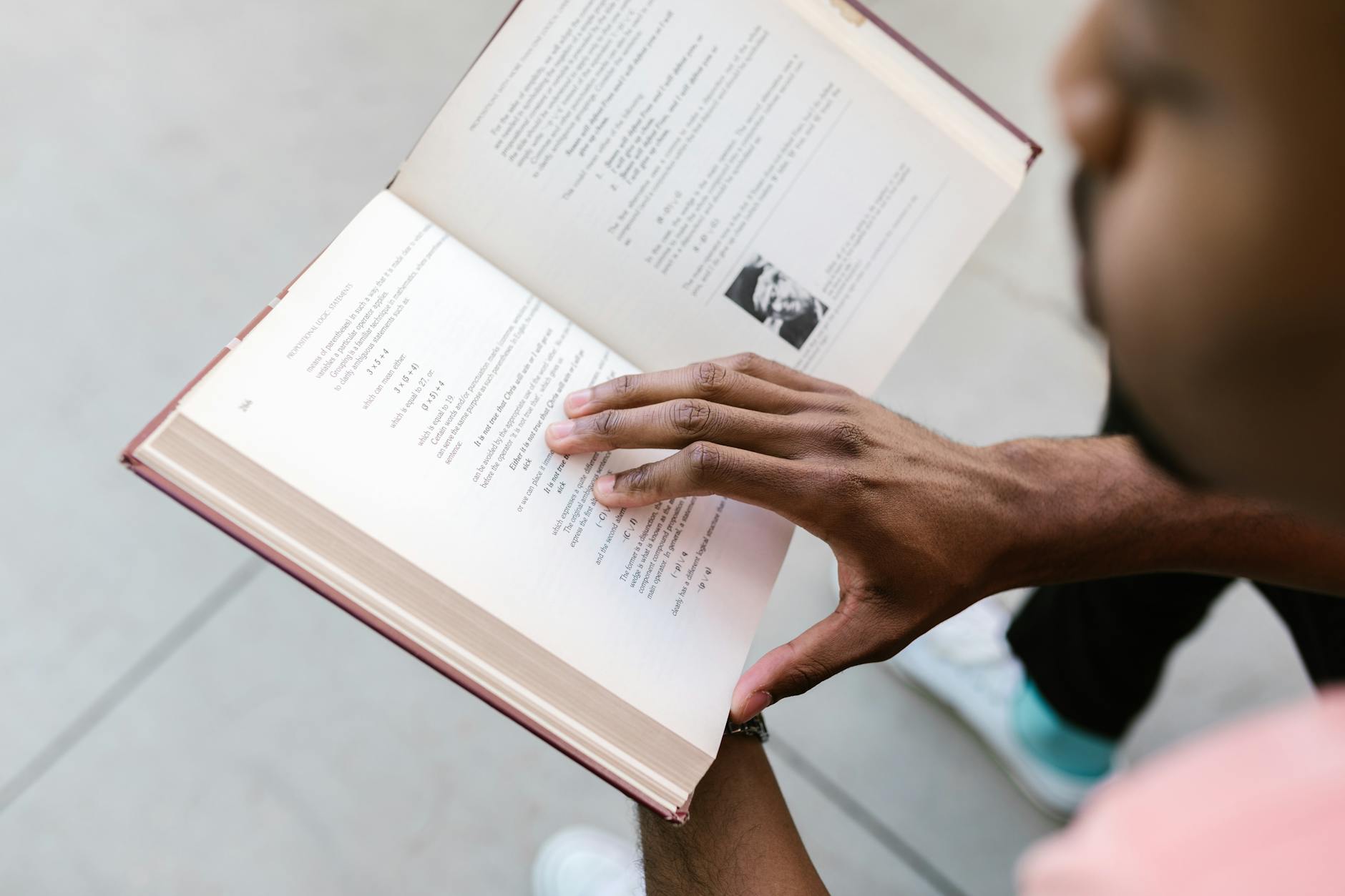 A primary student smiling proudly while holding a thin chapter book with small illustrations and short paragraphs.