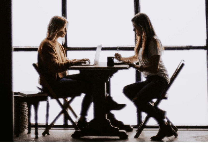 two women at a desk working on a laptop
