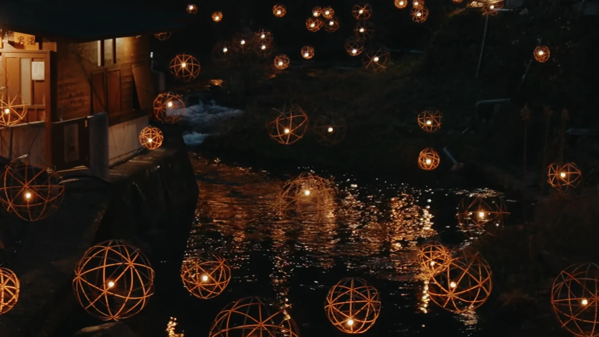 Yuakari lantern spheres reflected on the river at Kurokawa Onsen