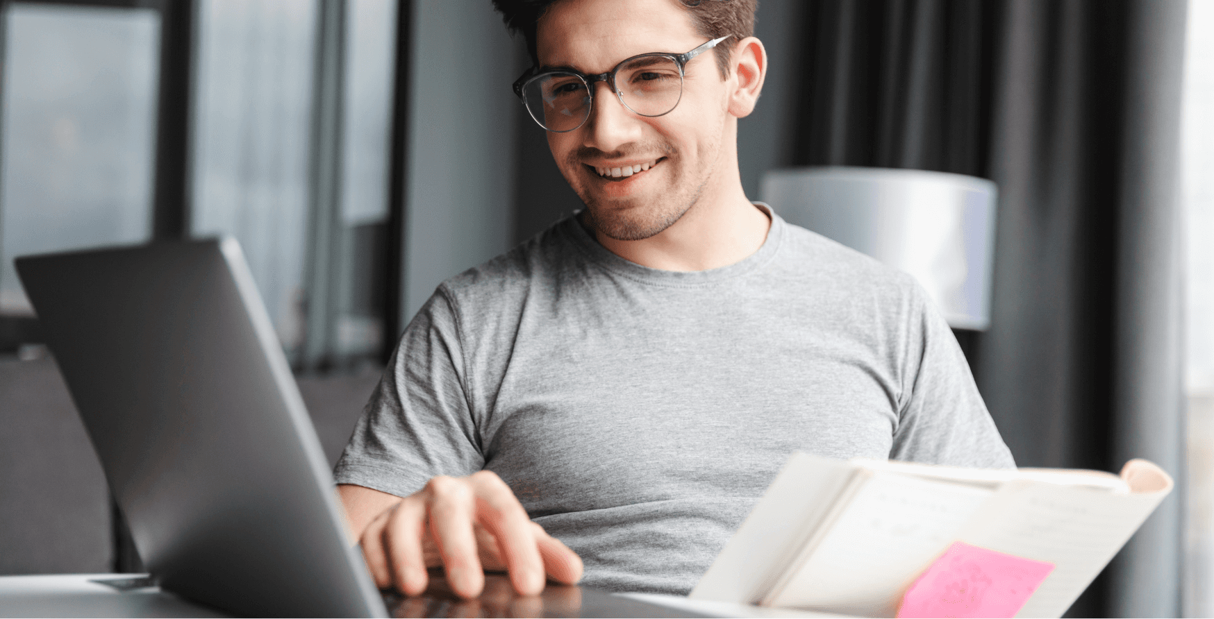 Eine lächelnde Person schaut auf einen Laptop