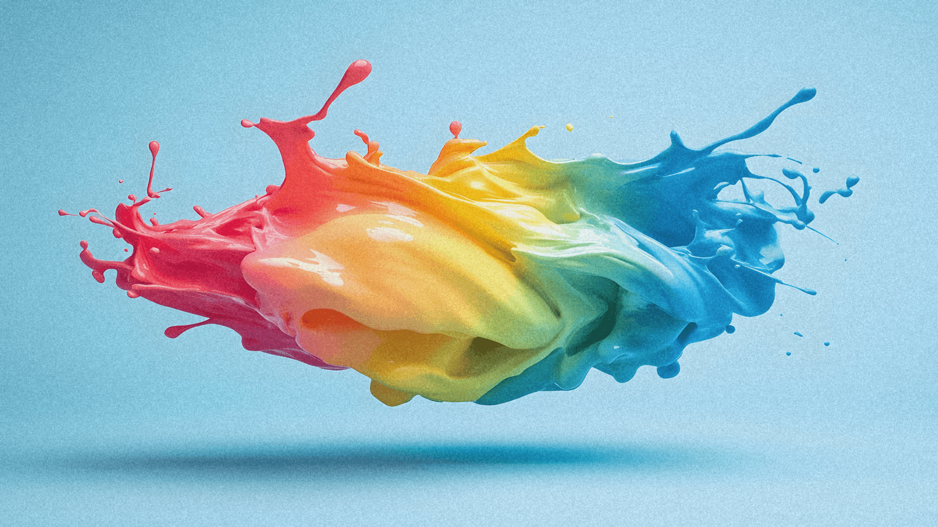Abstract splash of vibrant colors—red, orange, yellow, green, and blue—against a light blue background.