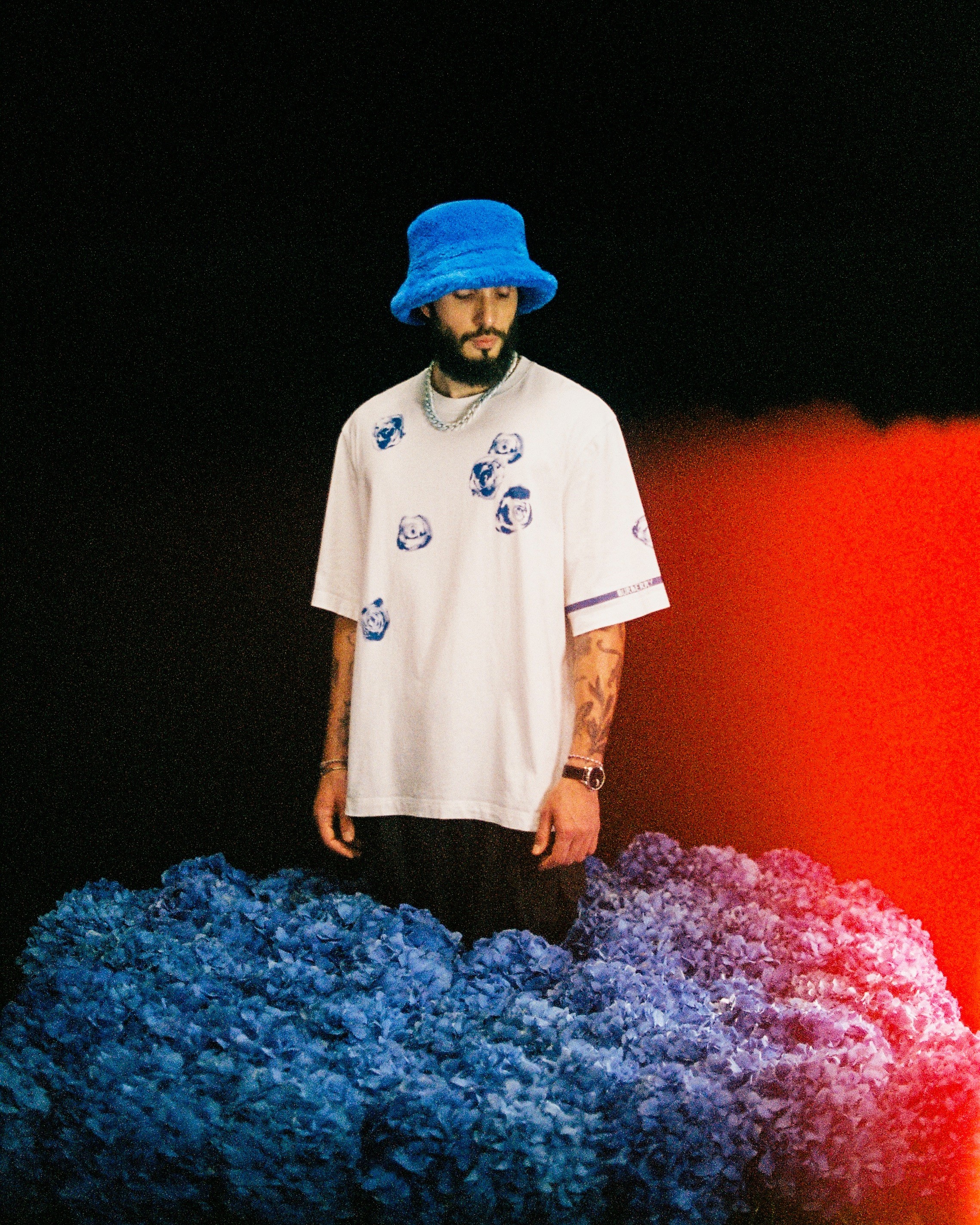 Portrait de Folamour portant son bob emblématique, avec un sourire chaleureux et une esthétique solaire.