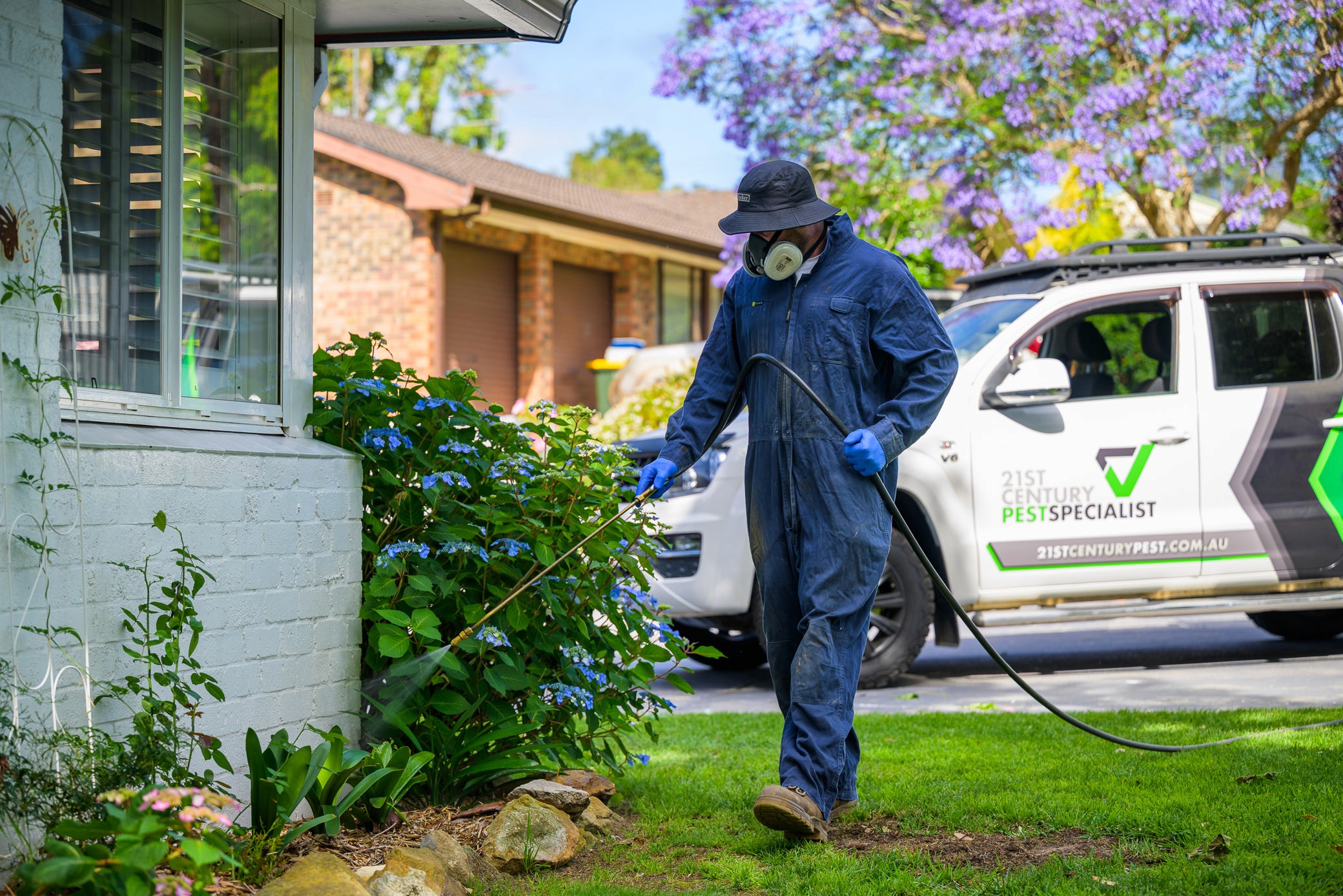 Pest technician spraying the outside perimiter of a house to prevent pests entering