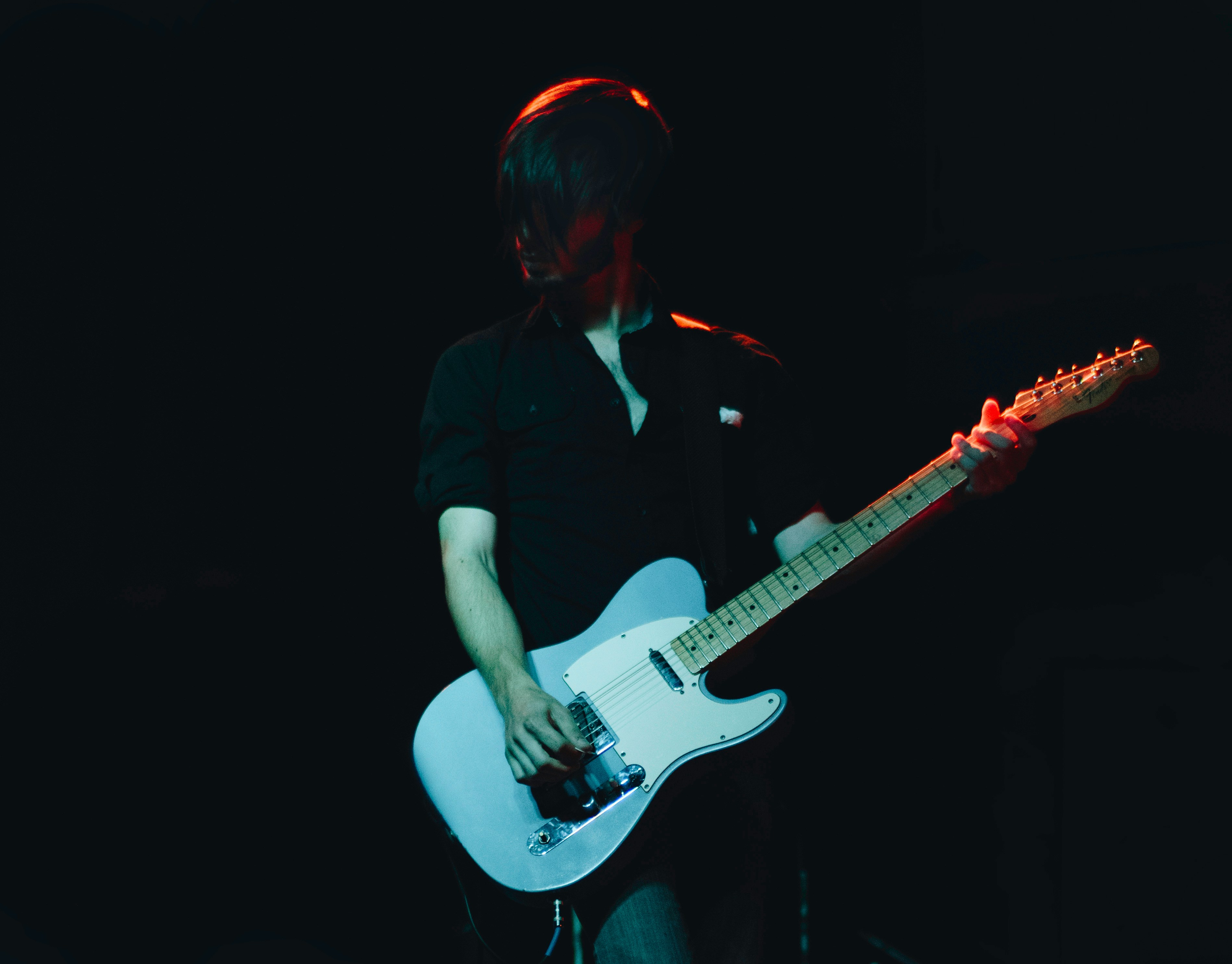 person with a guitar on stage - How To Write Pop Songs