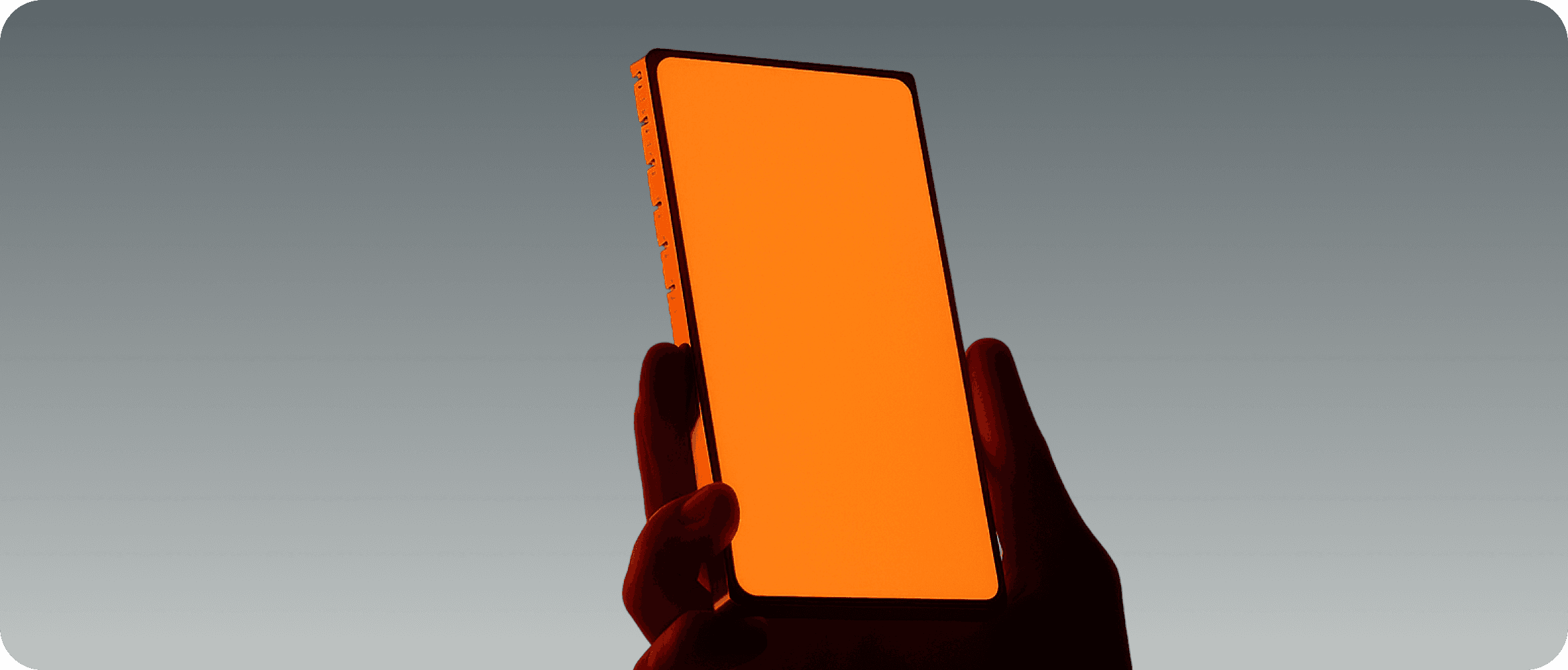 Smartphone with orange gradient screen held against gray background