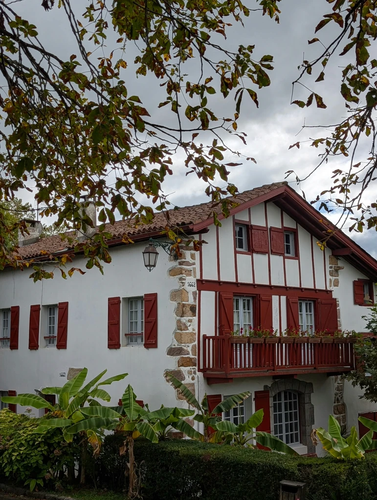Traditional white Basque house with red shutters and a wooden balcony