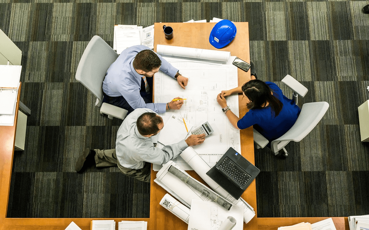 Team discussing plans with documents and calculator