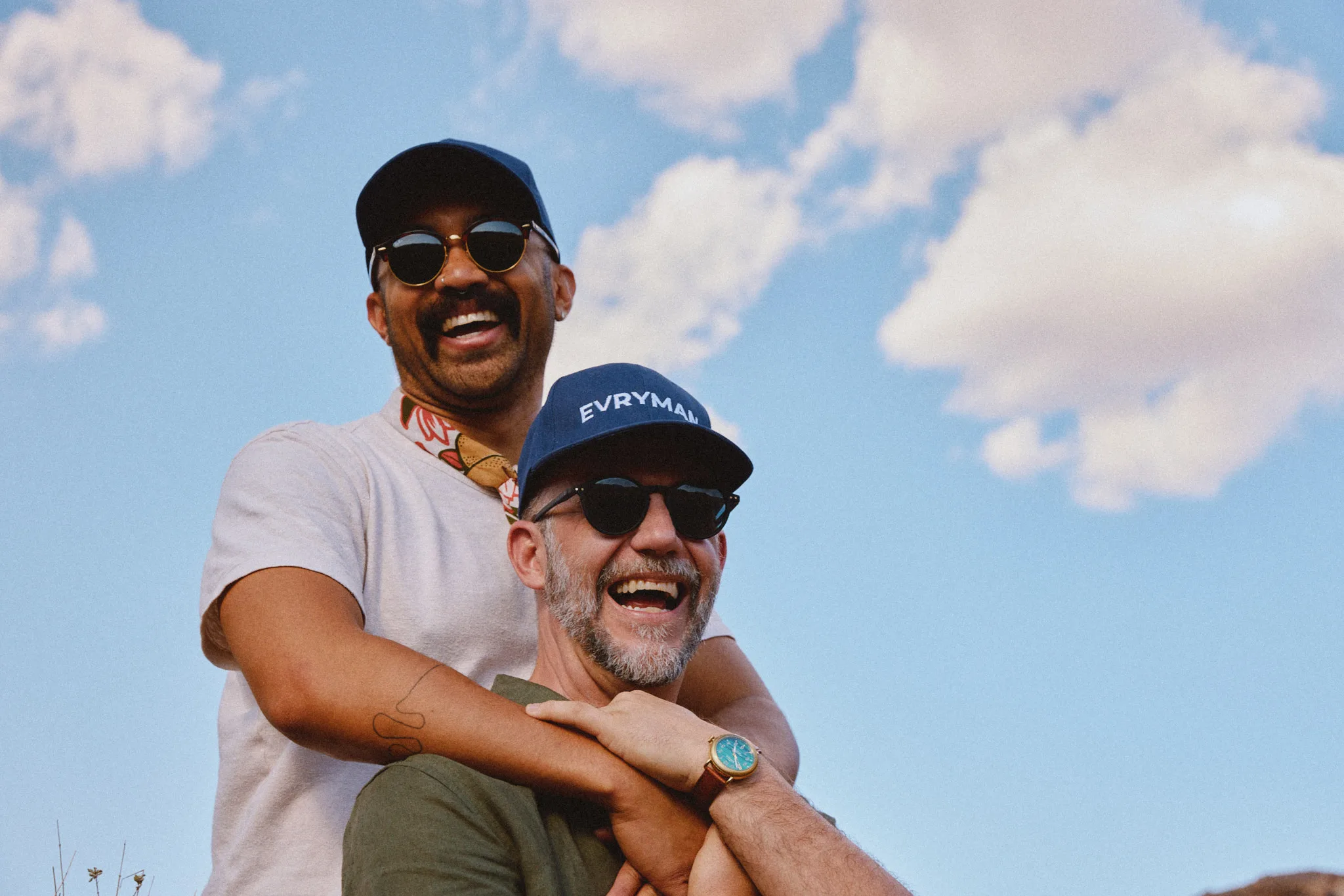 two men laughing in evryman caps — portrait photography by Tom Kubik