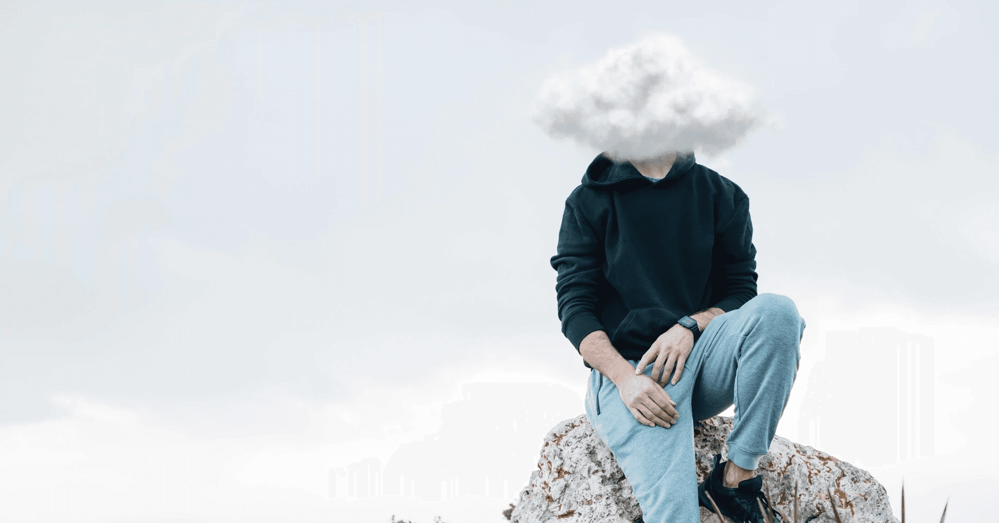 A person sitting on a rock, wearing a sweatshirt, with a cloud covering their head against a cloudy sky.