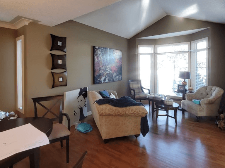 A front room with furniture at an angle. Nothing feels quite right. There is no area rug. The walls are taupe/ olive green and make the room feel dark.