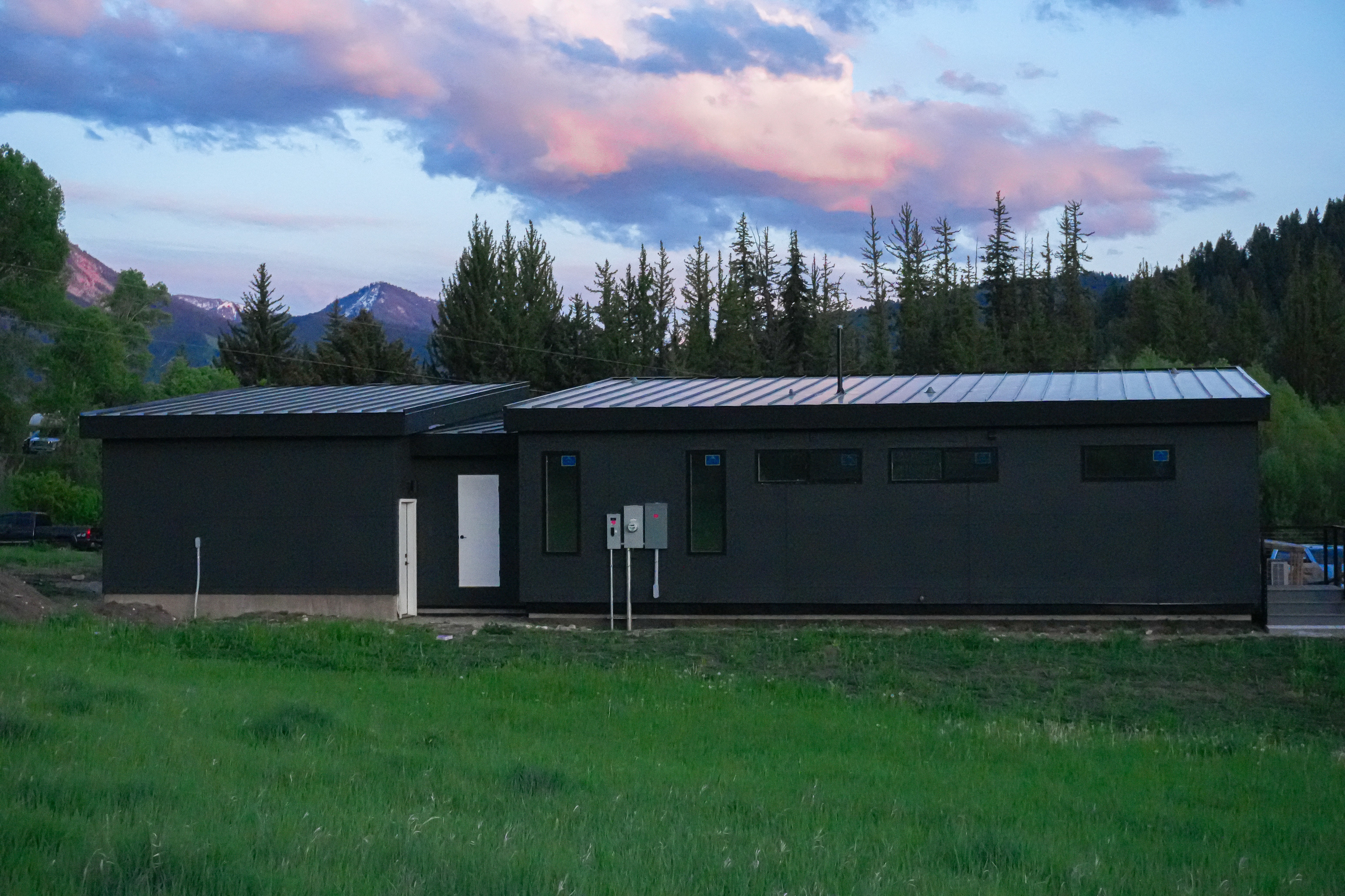 A modular home in Jackson Wyoming from behind at dusk showing the large yard.
