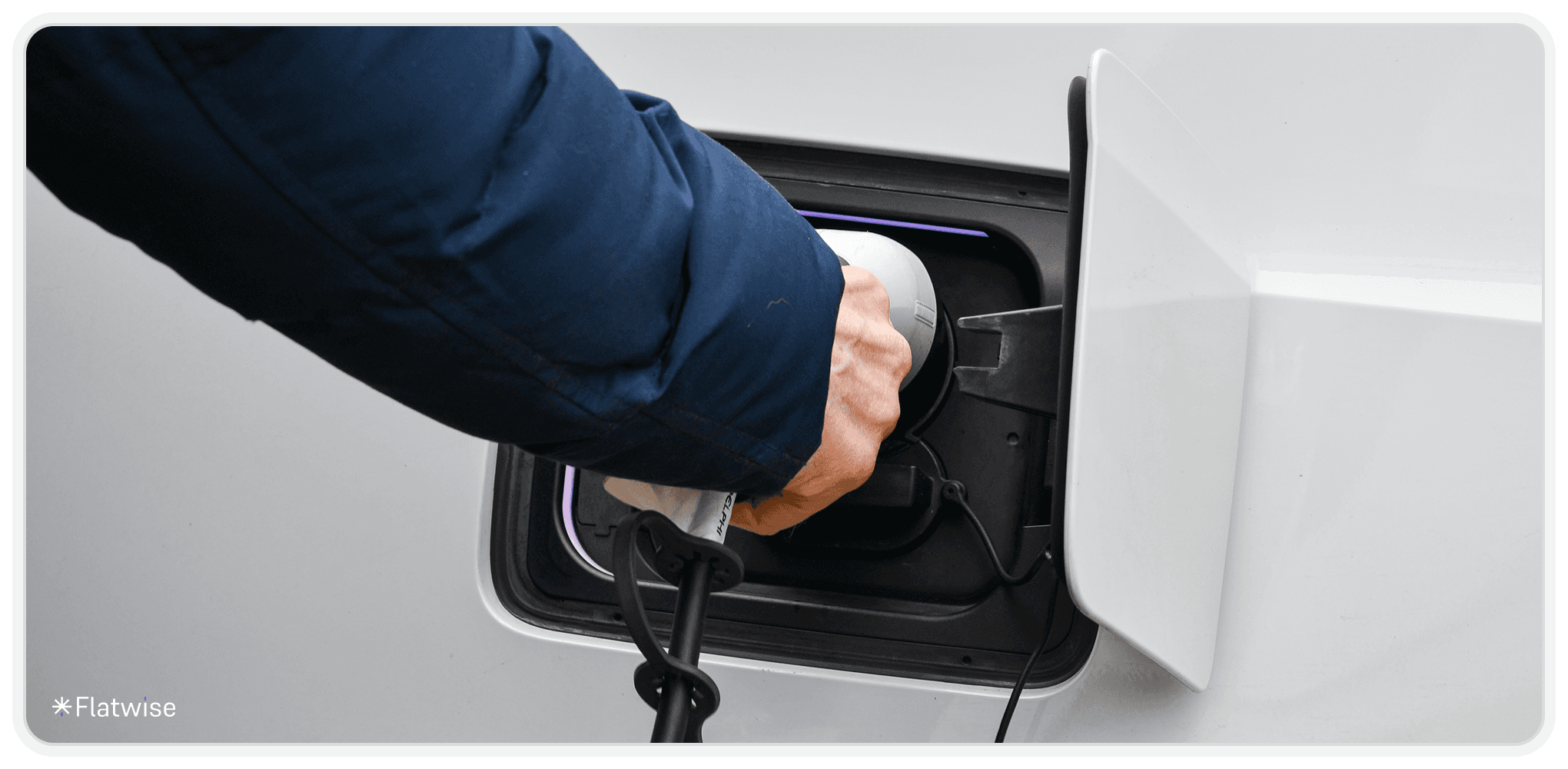 Hand steckt E-Ladezapfsäule in Auto.