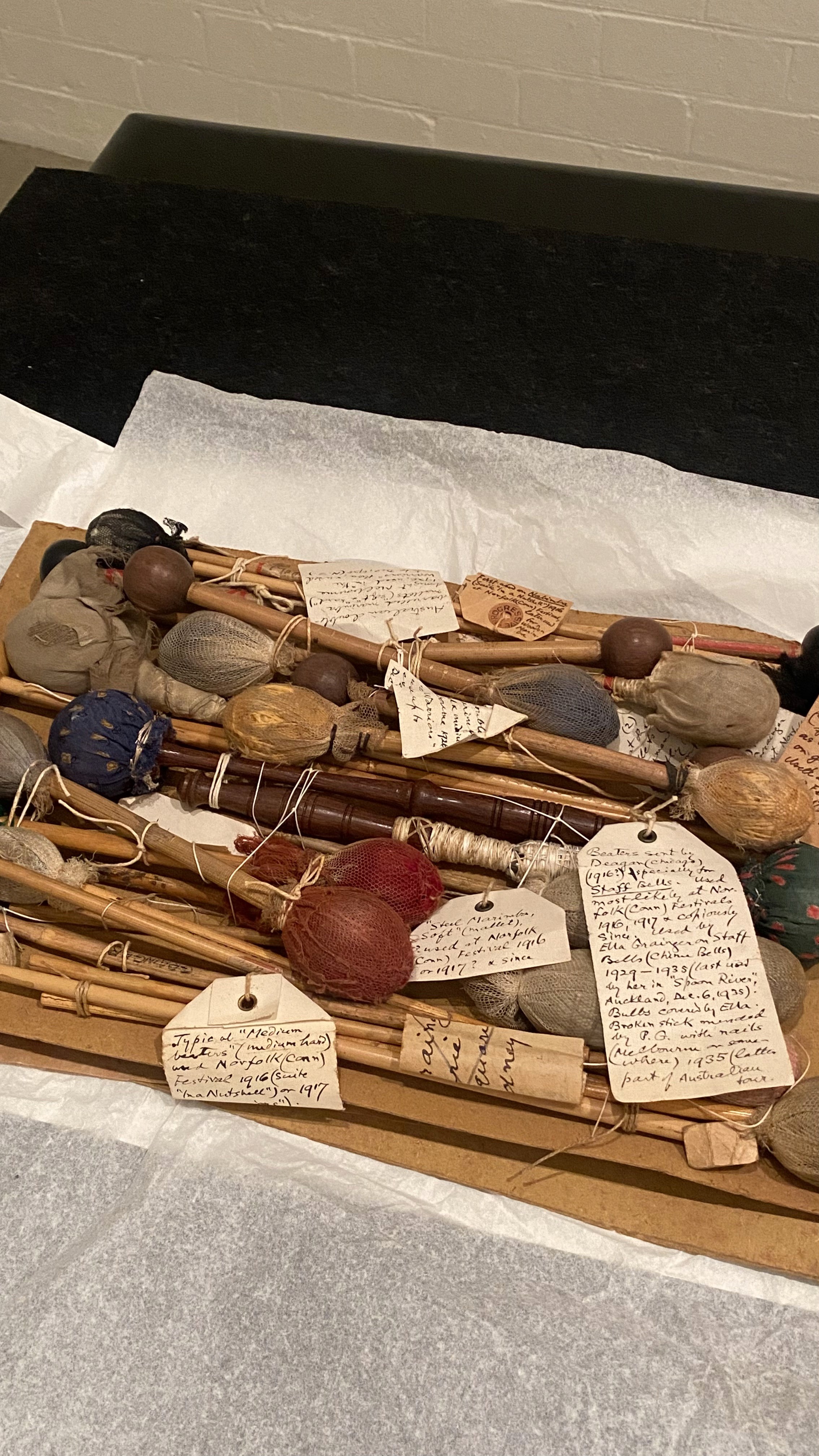 A collection of percussion instruments with handwritten labels attached to each one in the Grainger Museum