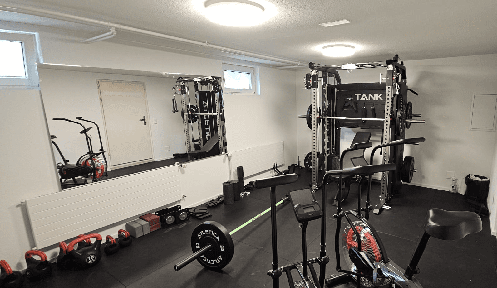 Hell beleuchteter Fitnessraum im Haus Raphael mit Heimtrainern, Hanteln und Gymnastikmatten zur Förderung der körperlichen Gesundheit.