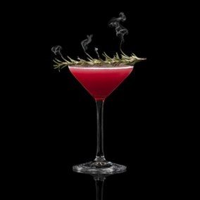 A closeup of a Pomegranate Bliss Martini drink against a dark background.