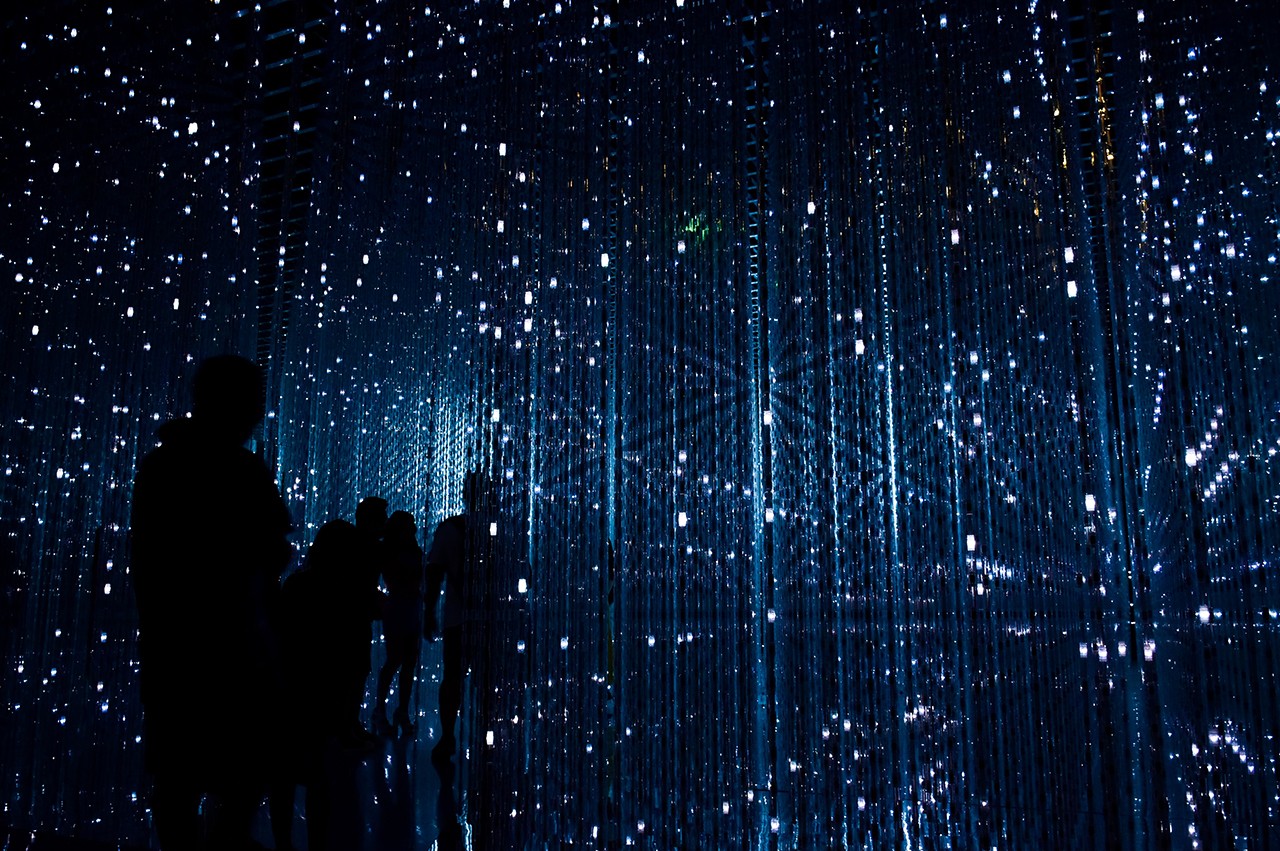 Art installation in a dark room with visitor silhouettes