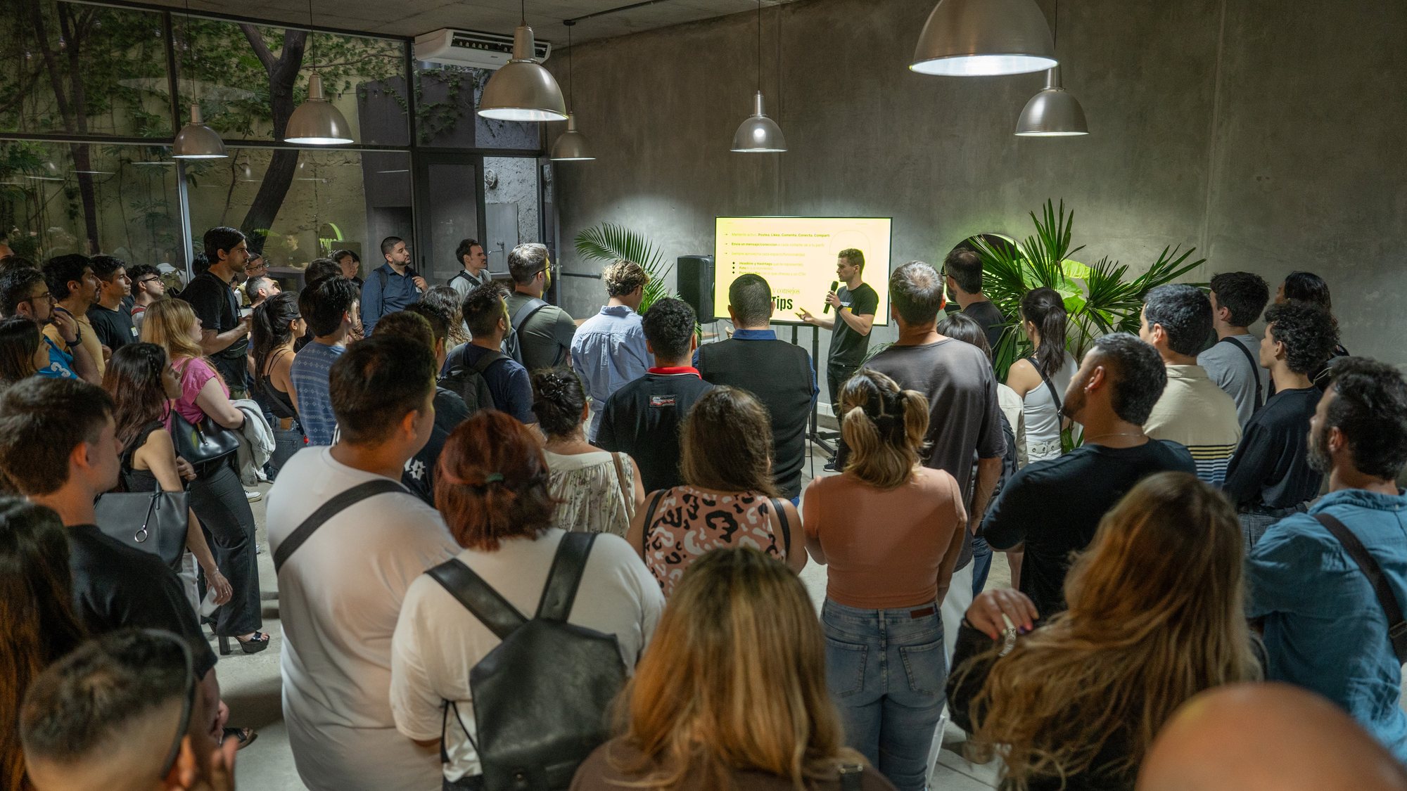 A packed Coderhouse gathering, crowd facing a speaker and a screen, 2020